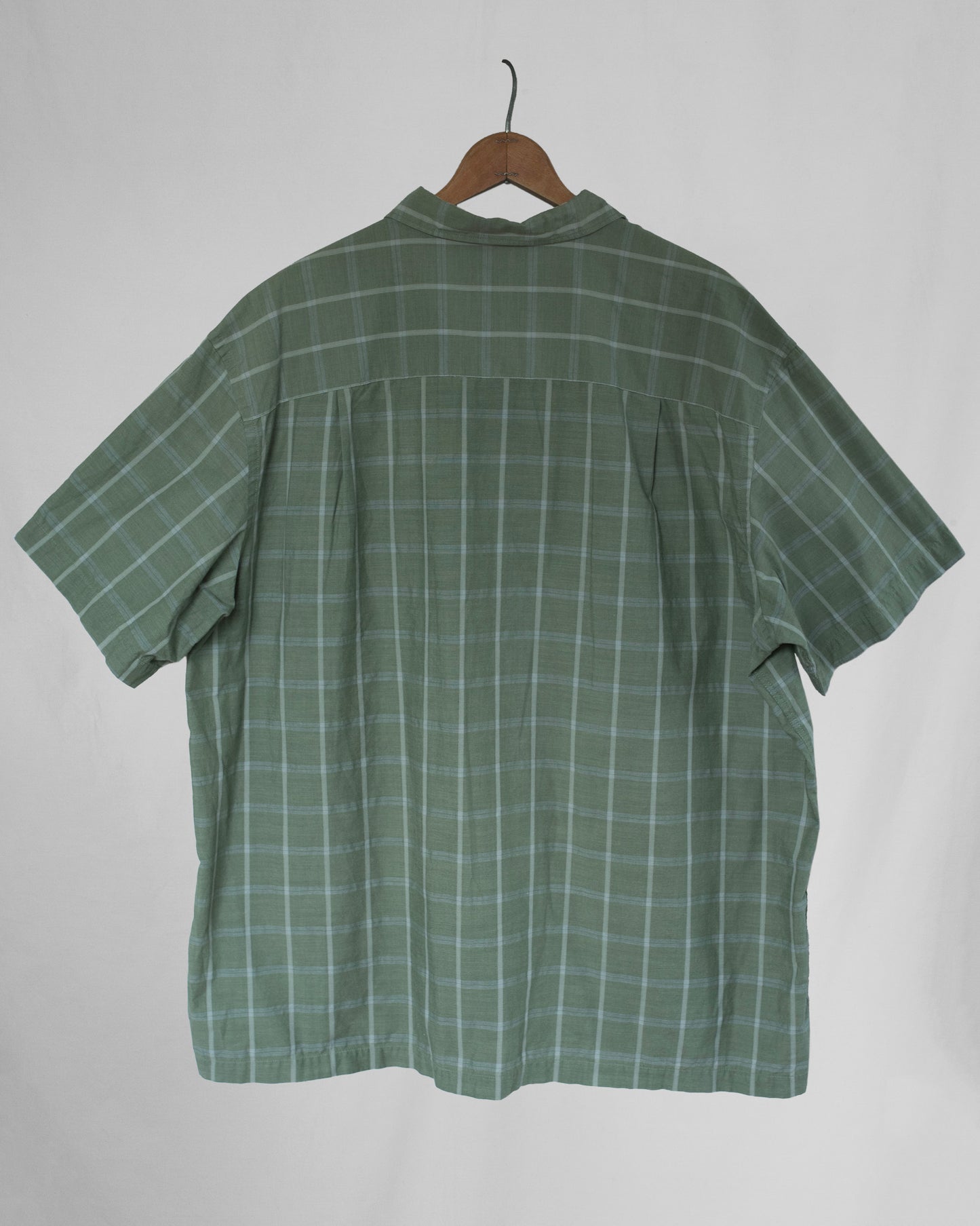 Green checkered shirt on a hanger against a white background