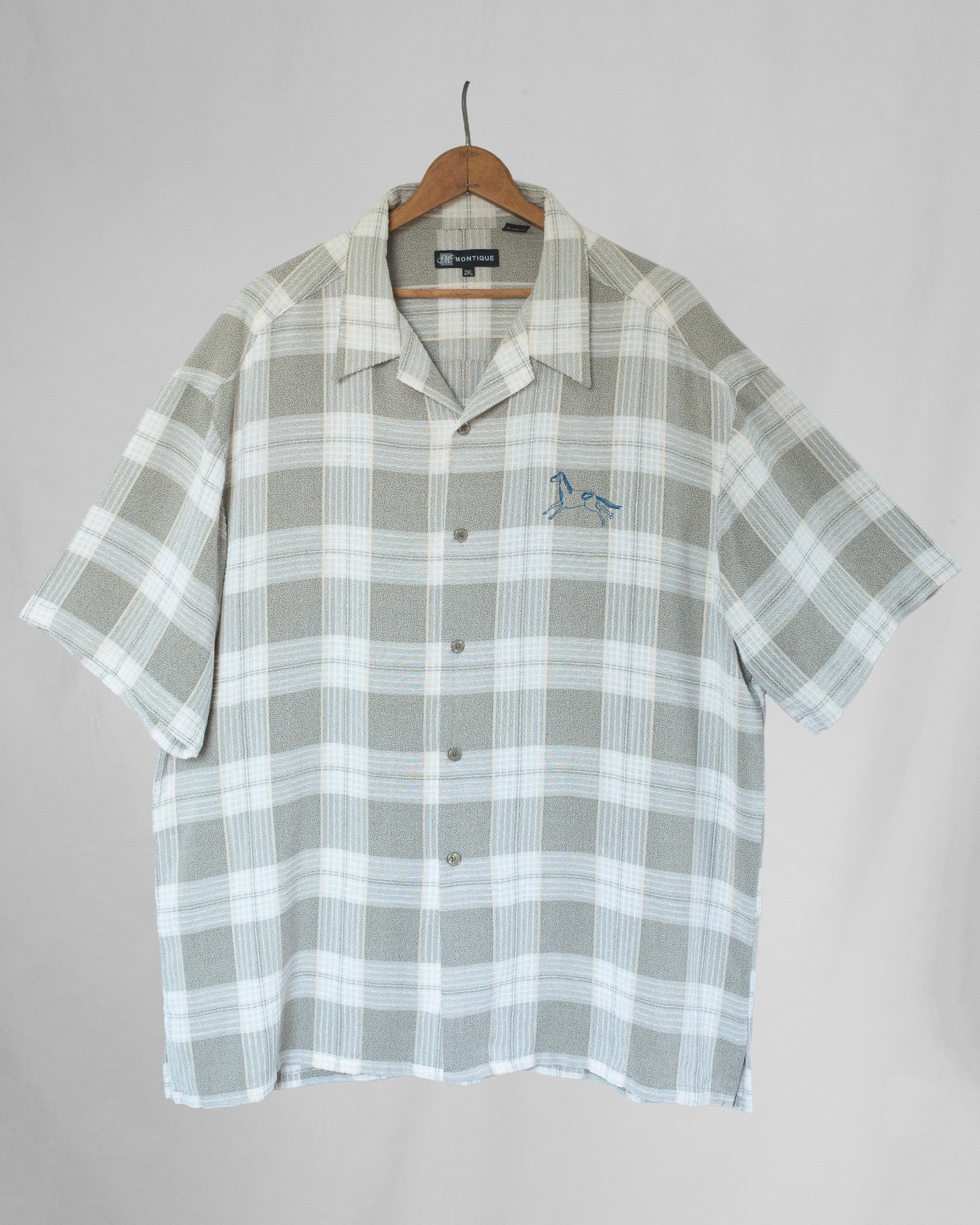 Plaid shirt with horse embroidery on a hanger against a plain background