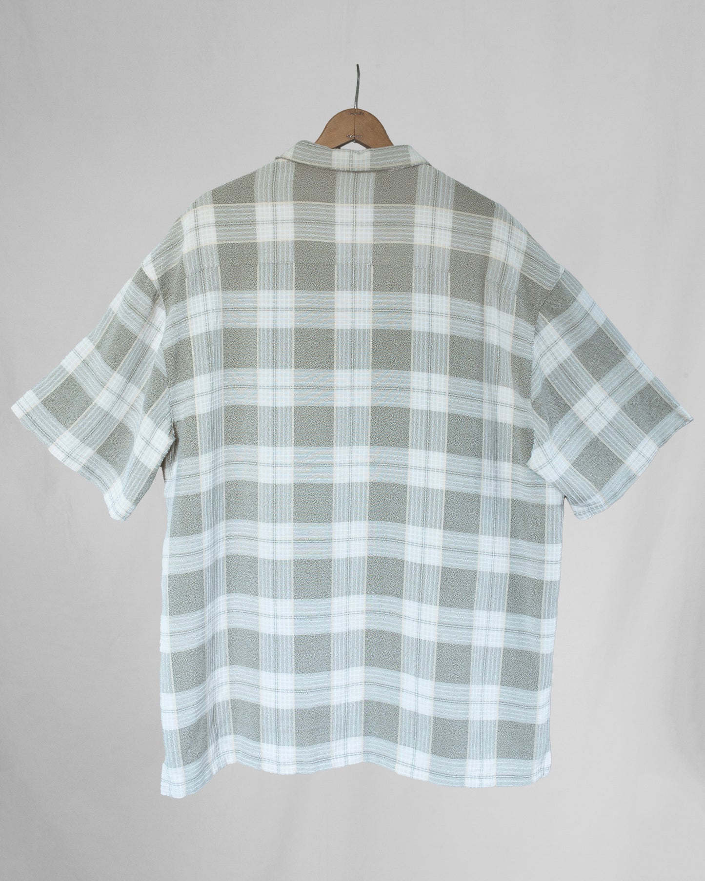 Plaid shirt on a hanger against a plain background