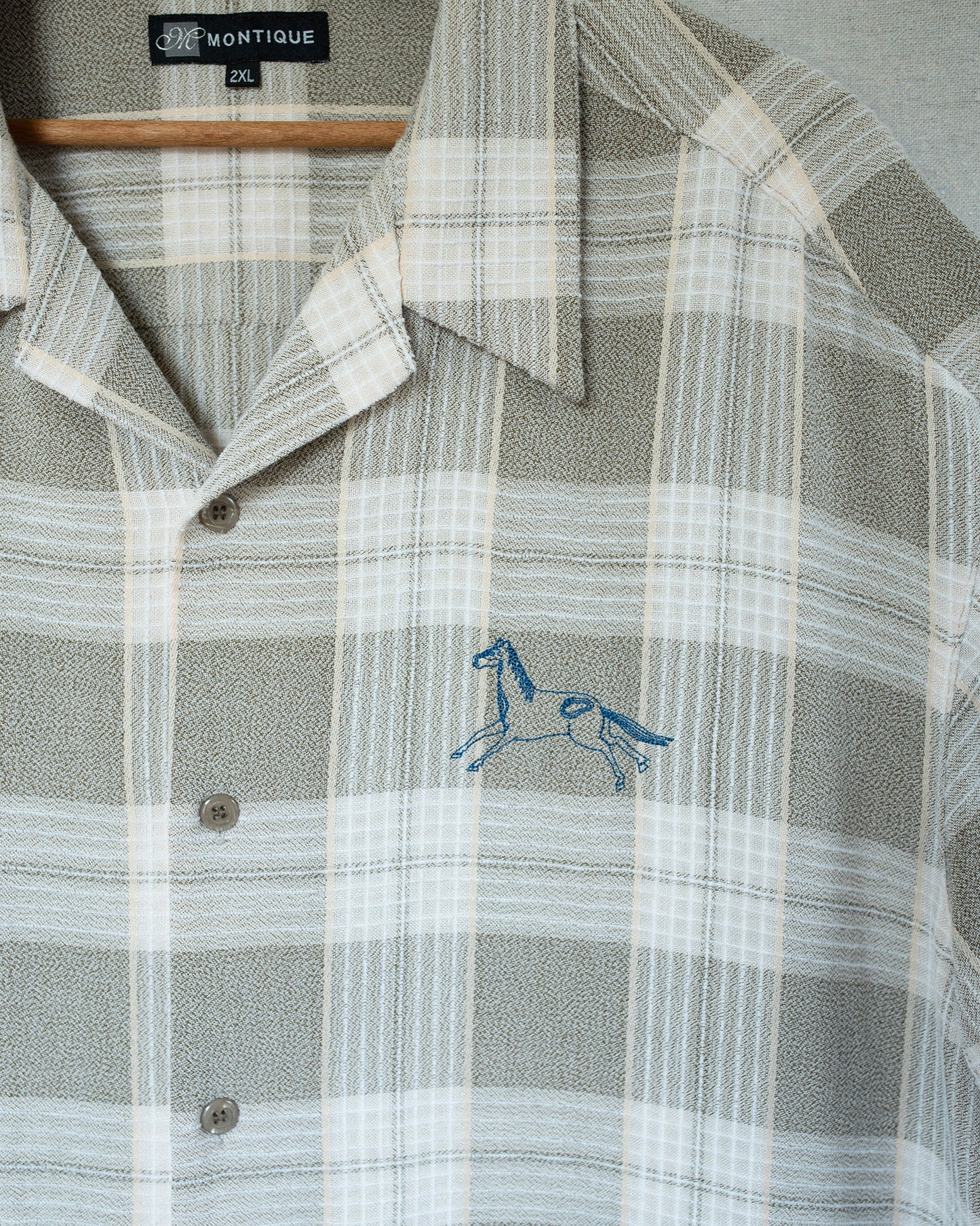 Plaid shirt with embroidered horse design on a hanger