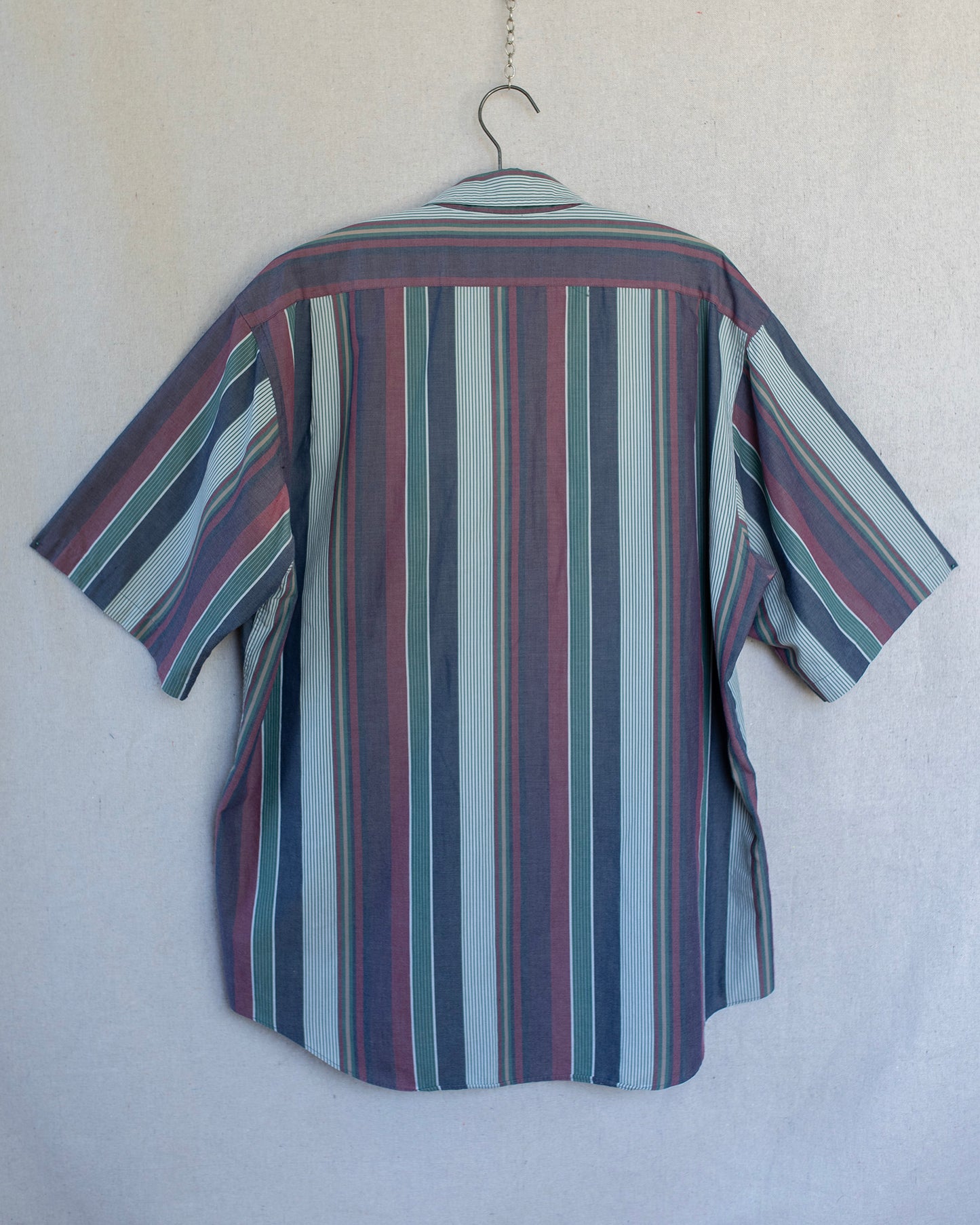 Striped shirt on a hanger against a plain background