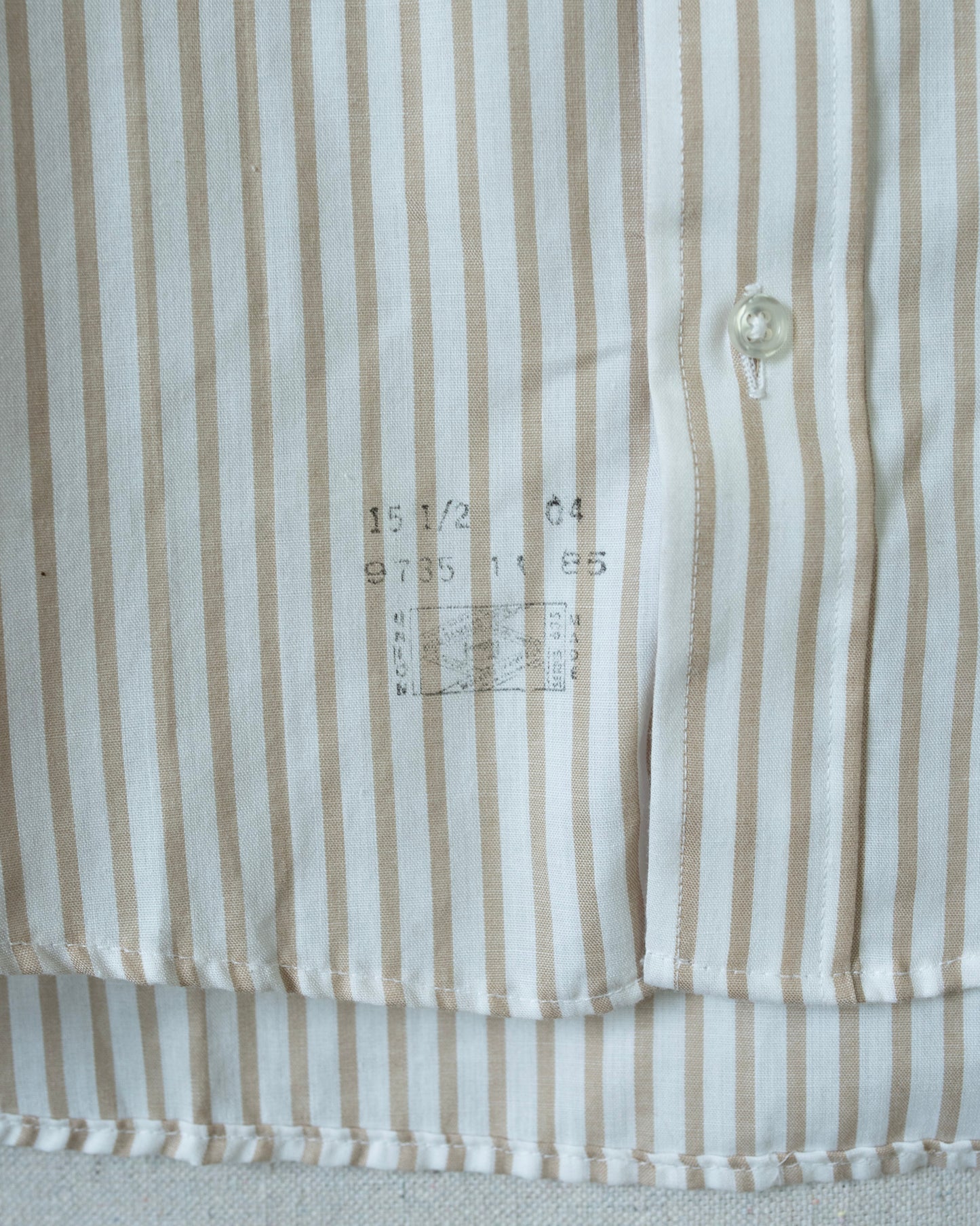 Bottom of shirt detail, stamped numbers on front of fabric above bottom seam - reads 15 1/2 04 9735 11 85 with union logo.