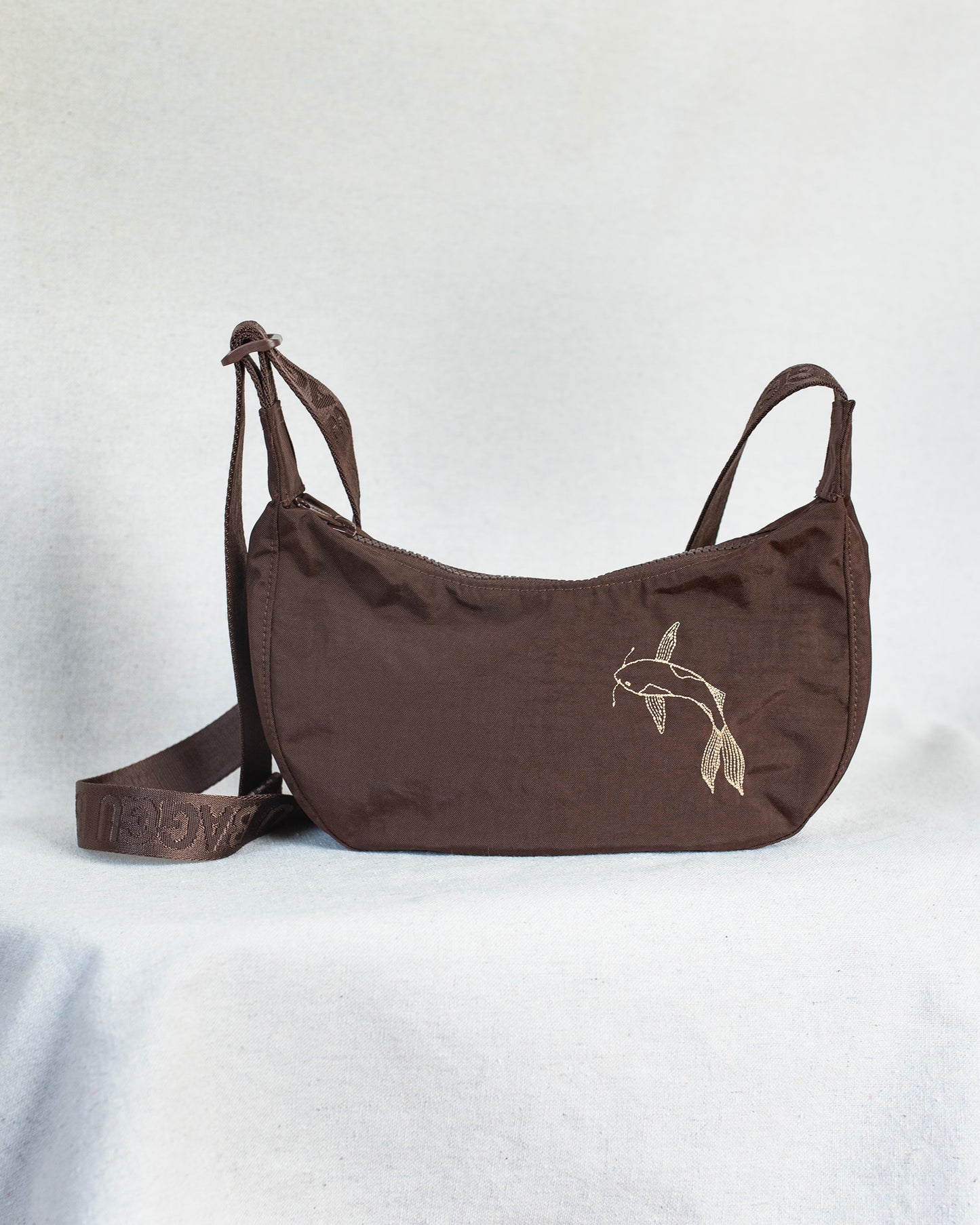 Brown shoulder bag with a koi fish embroidery on a white background