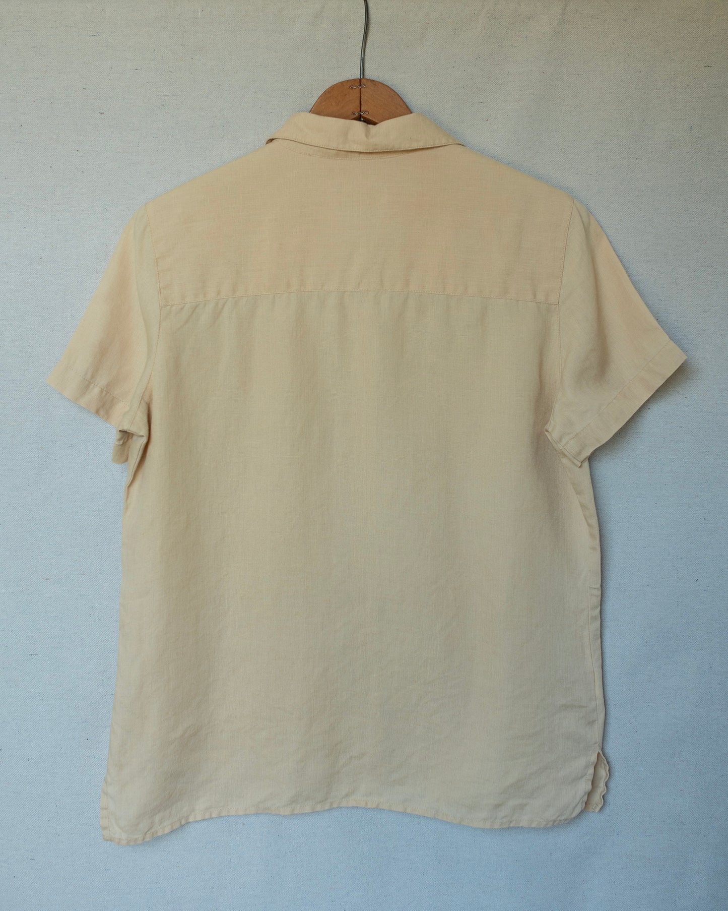 Pale yellow shirt hanging in front of a canvas tarp