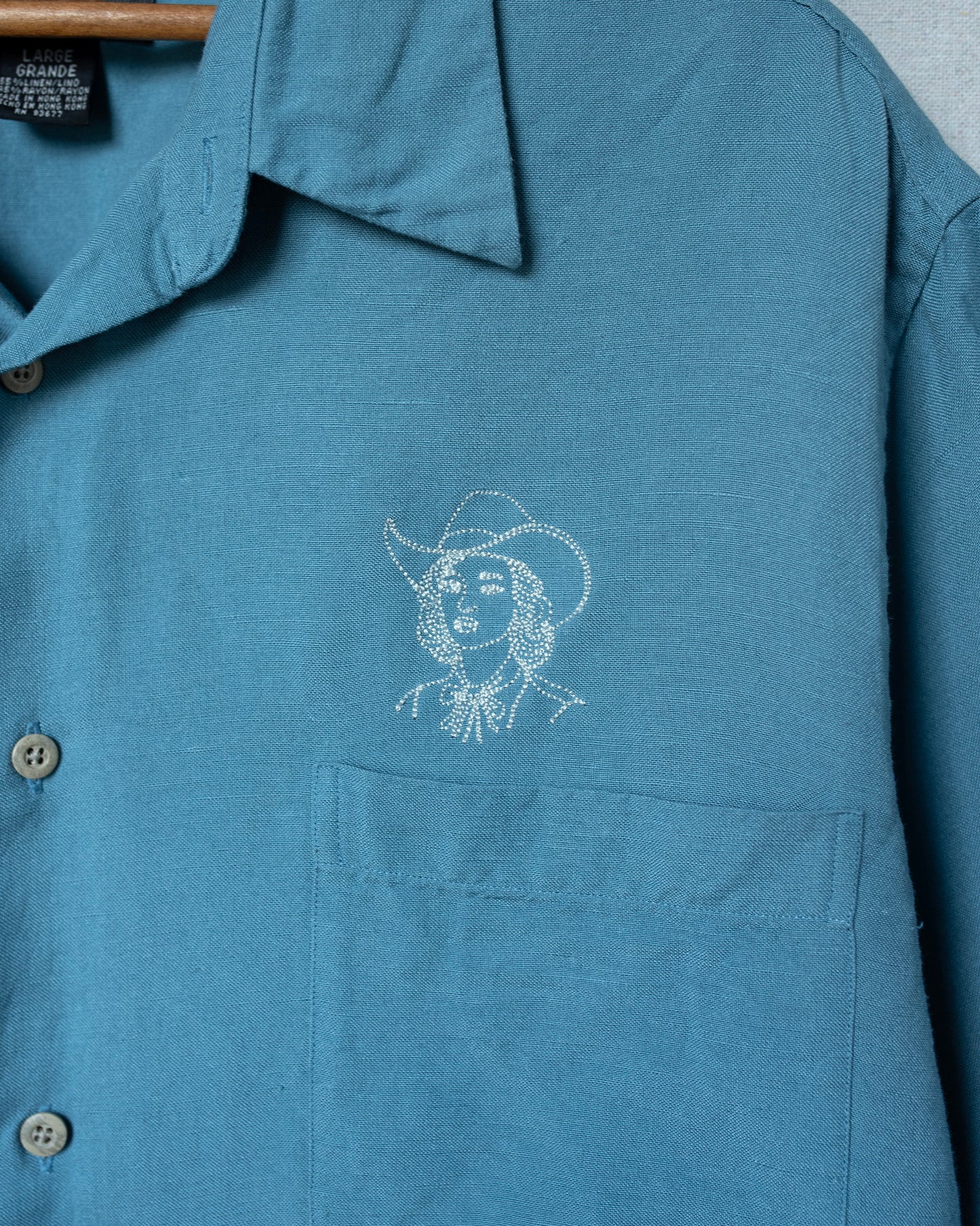 Blue shirt with a white embroidered design on a gray background