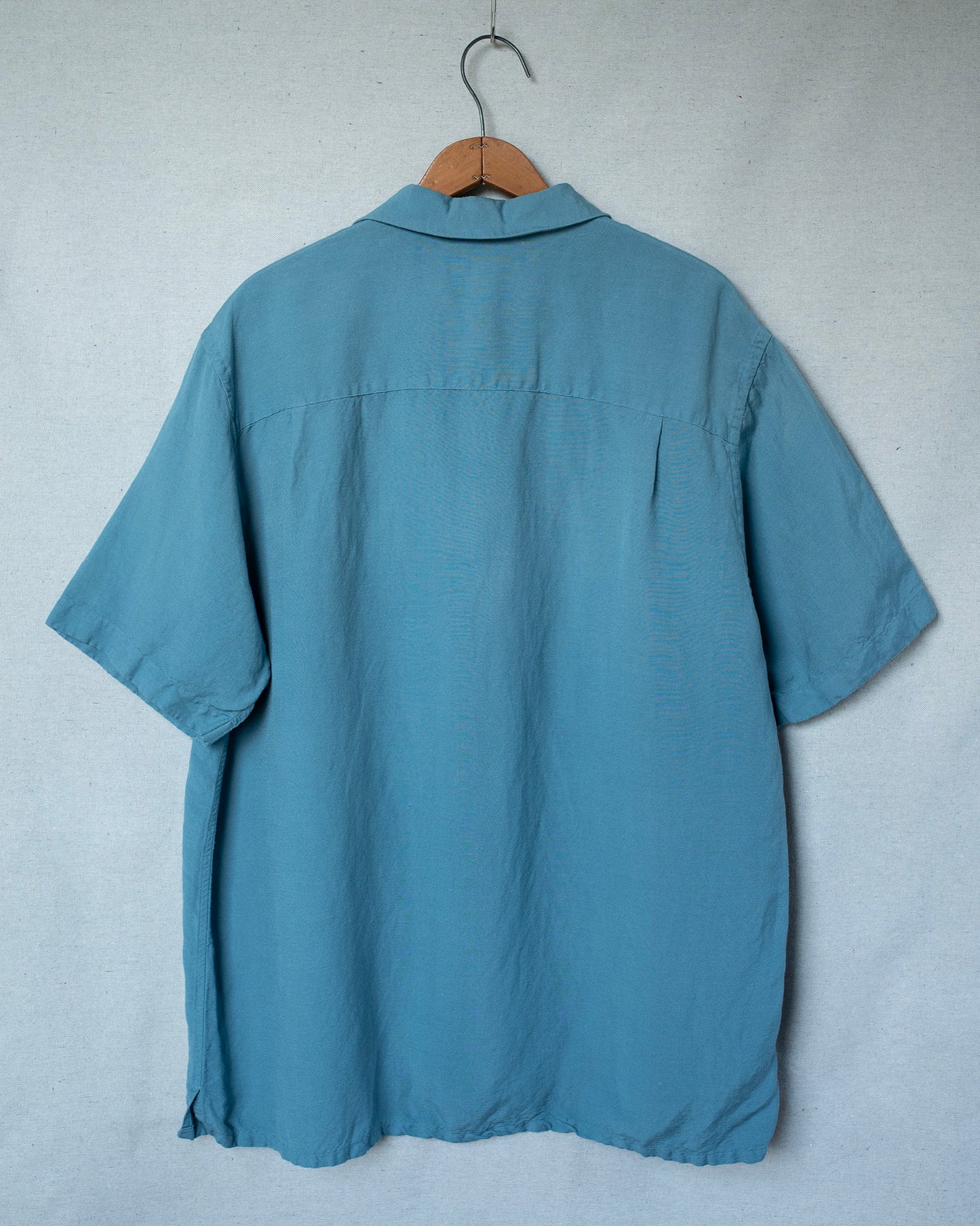 Blue shirt on a hanger against a plain background