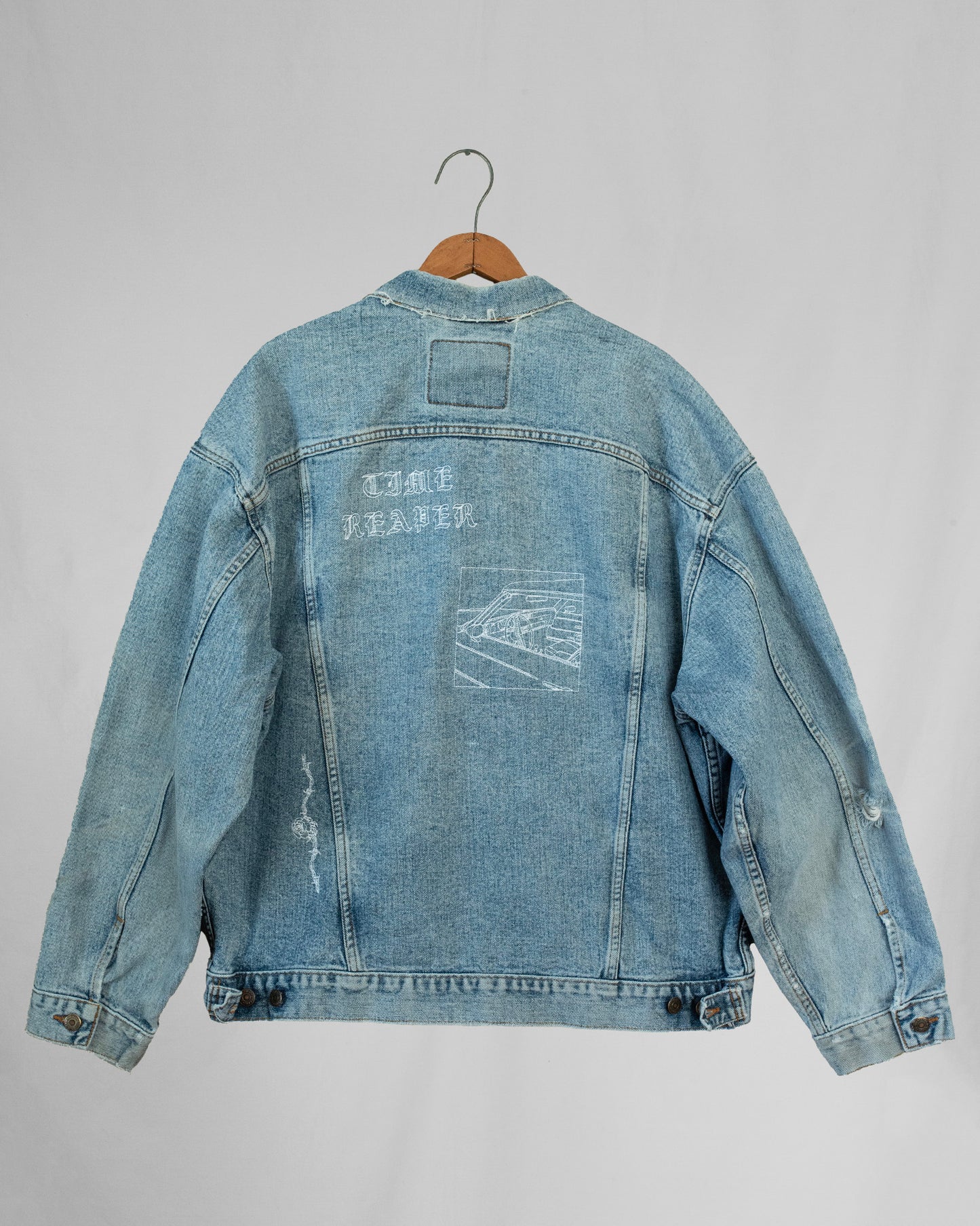 1990s Levis denim jacket with embroidery and a boxy fit, displayed on a hanger against a white background.