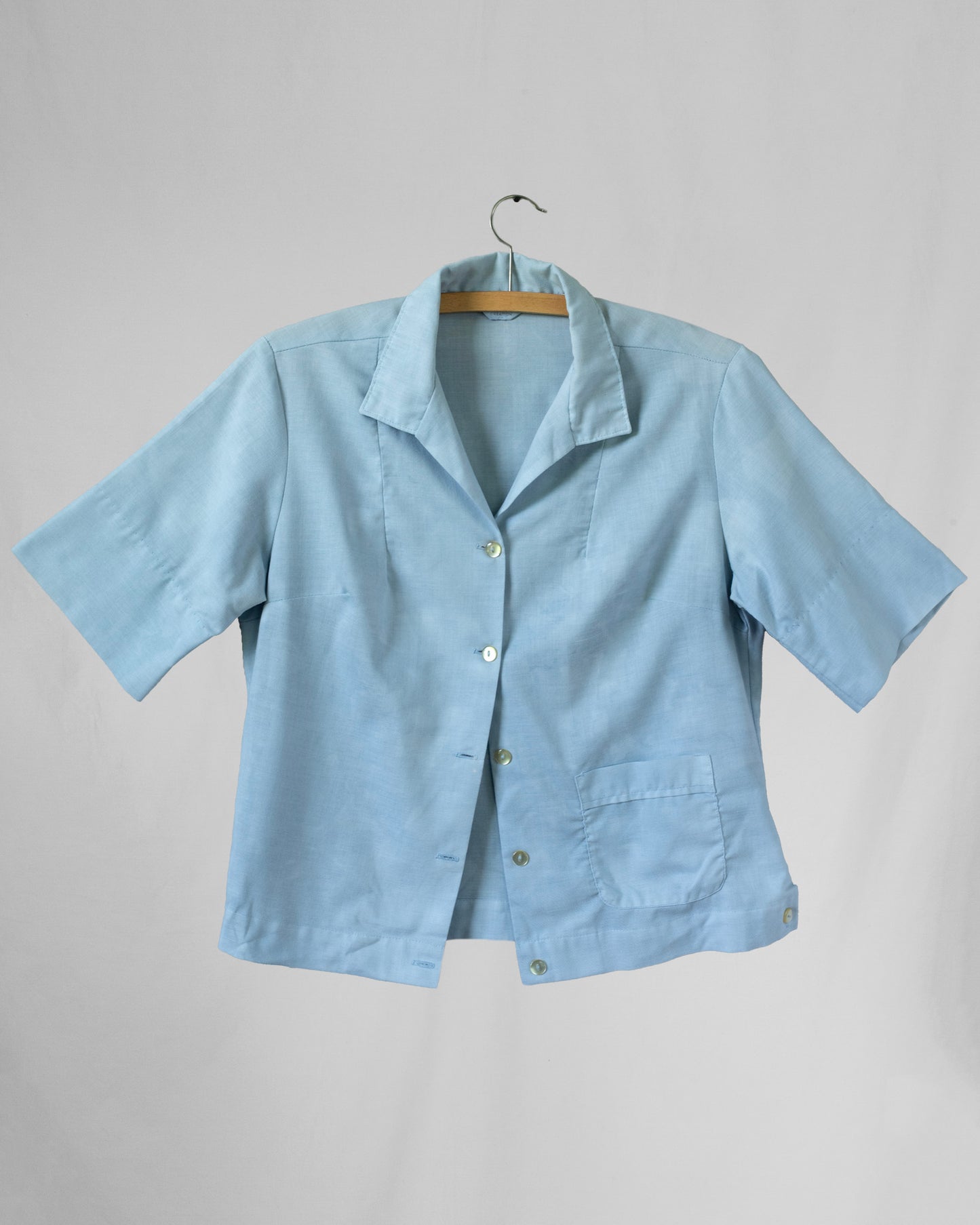 Light blue shirt on a hanger against a gray background
