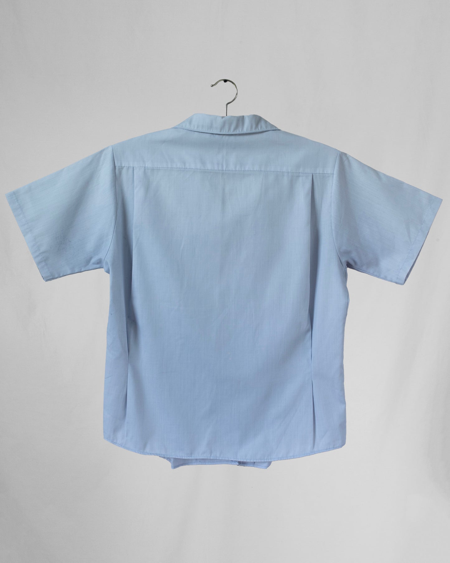 Light blue shirt on a hanger against a gray background