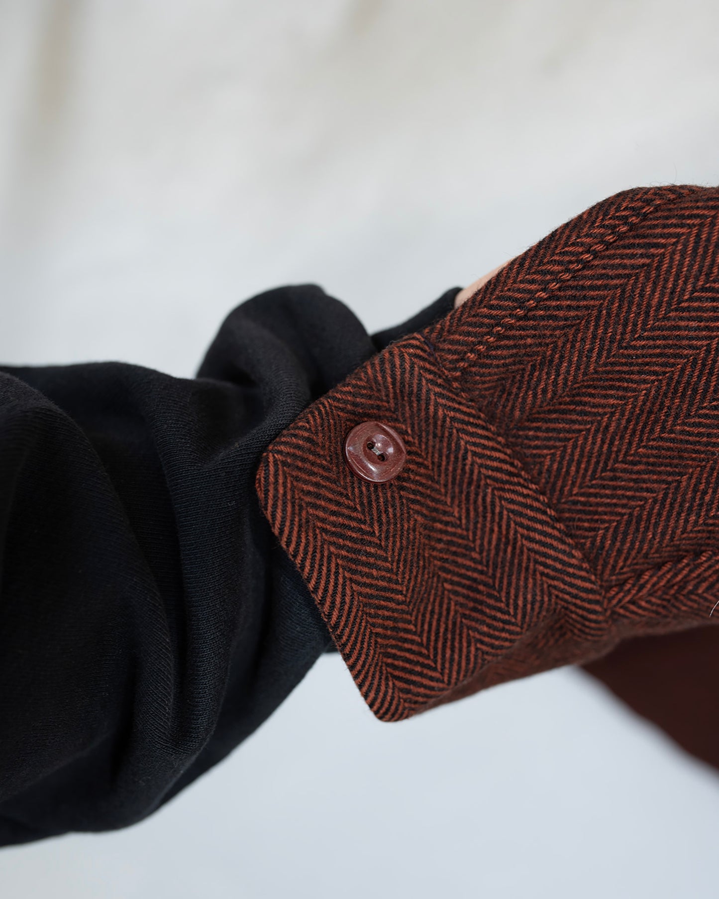Close-up of a brown herringbone fabric with button.