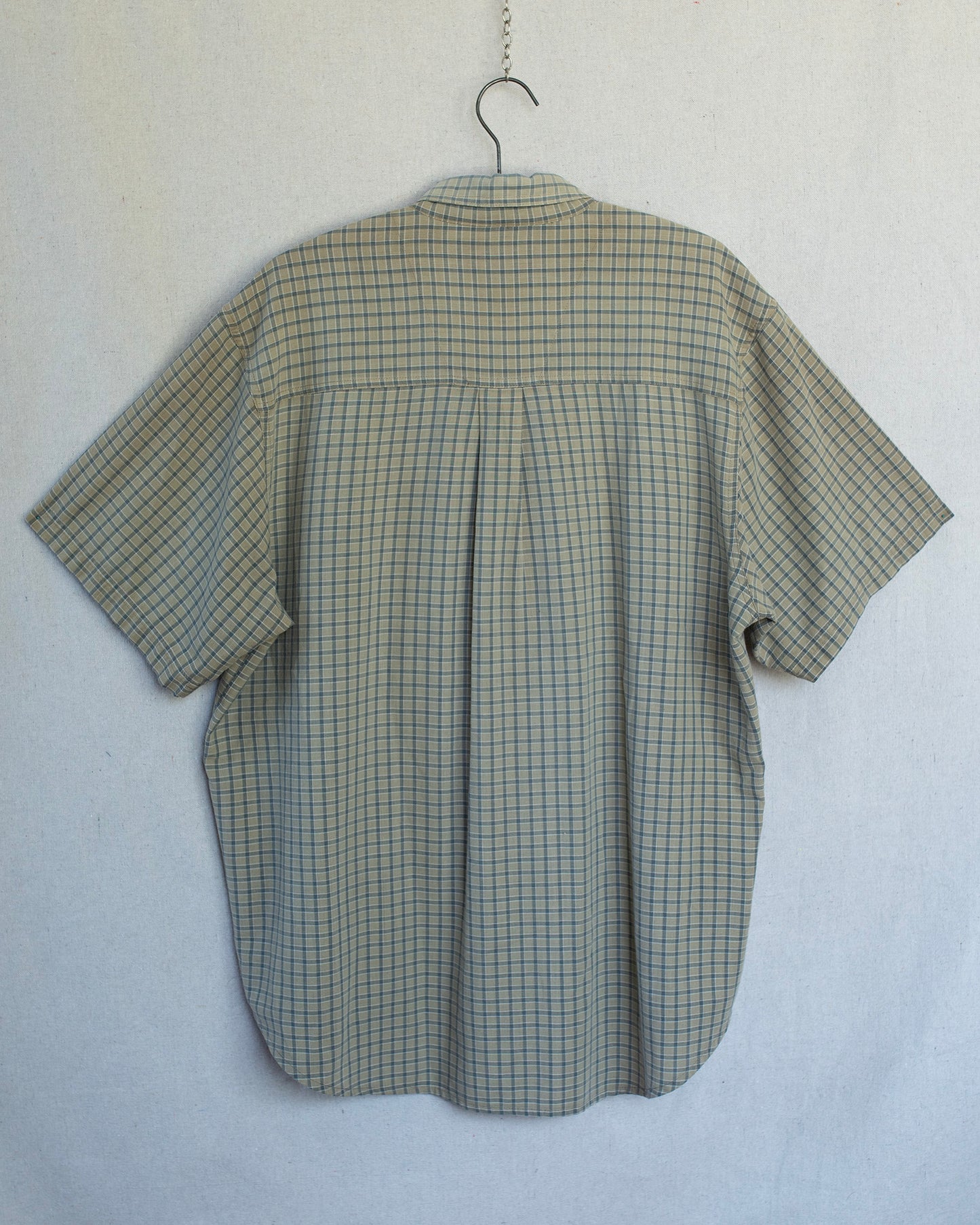 Green checkered shirt on a hanger against a white background