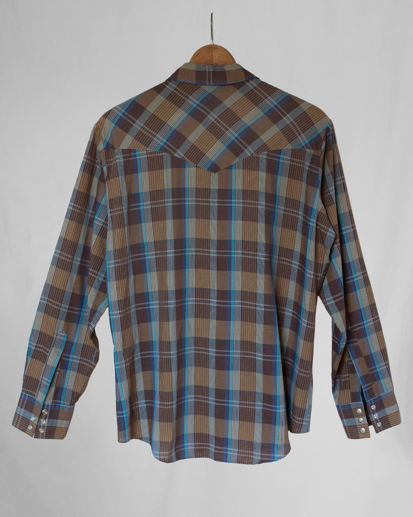Plaid pearl snap back hanging on a hanger.