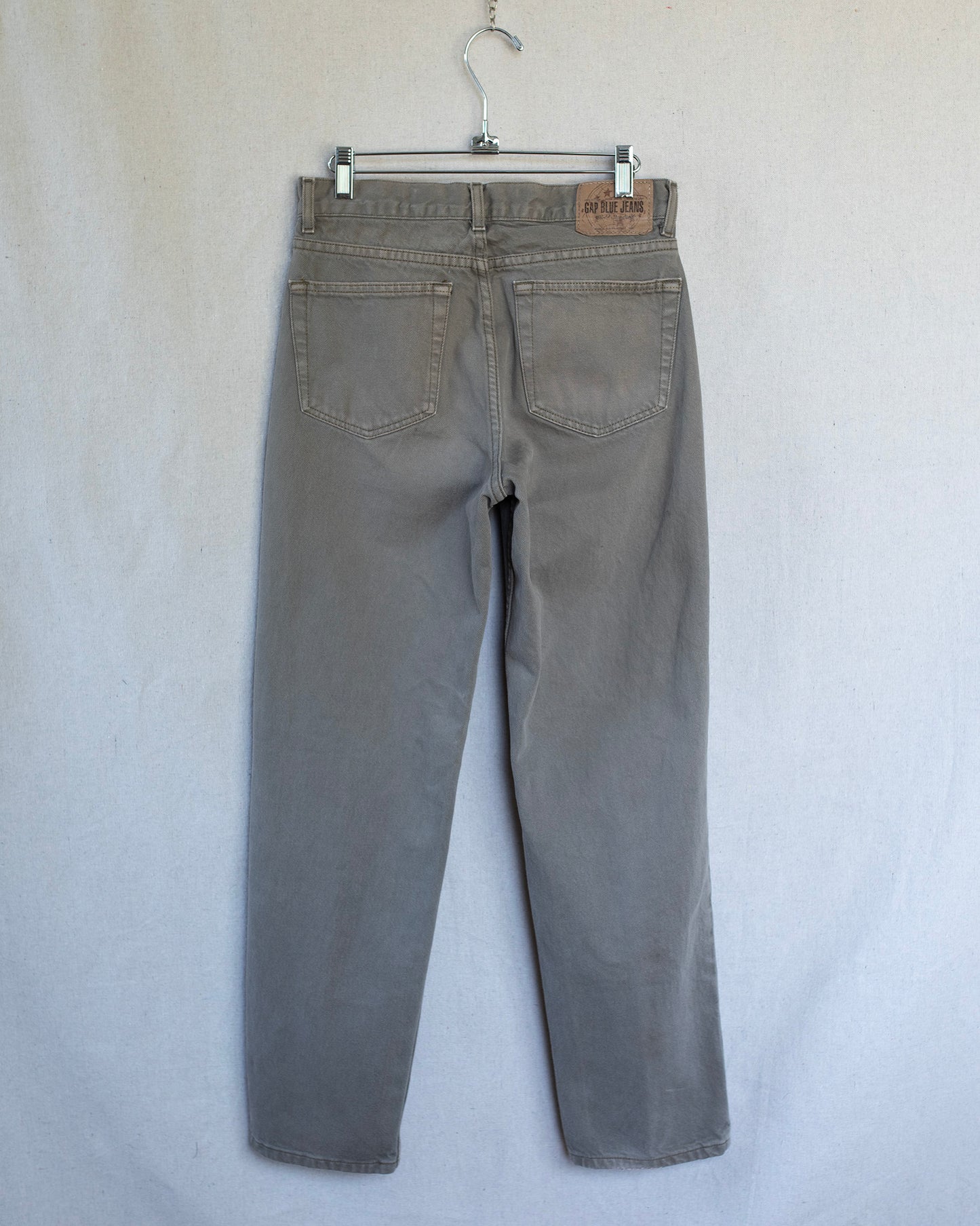 Brown jeans on a hanger against a white background