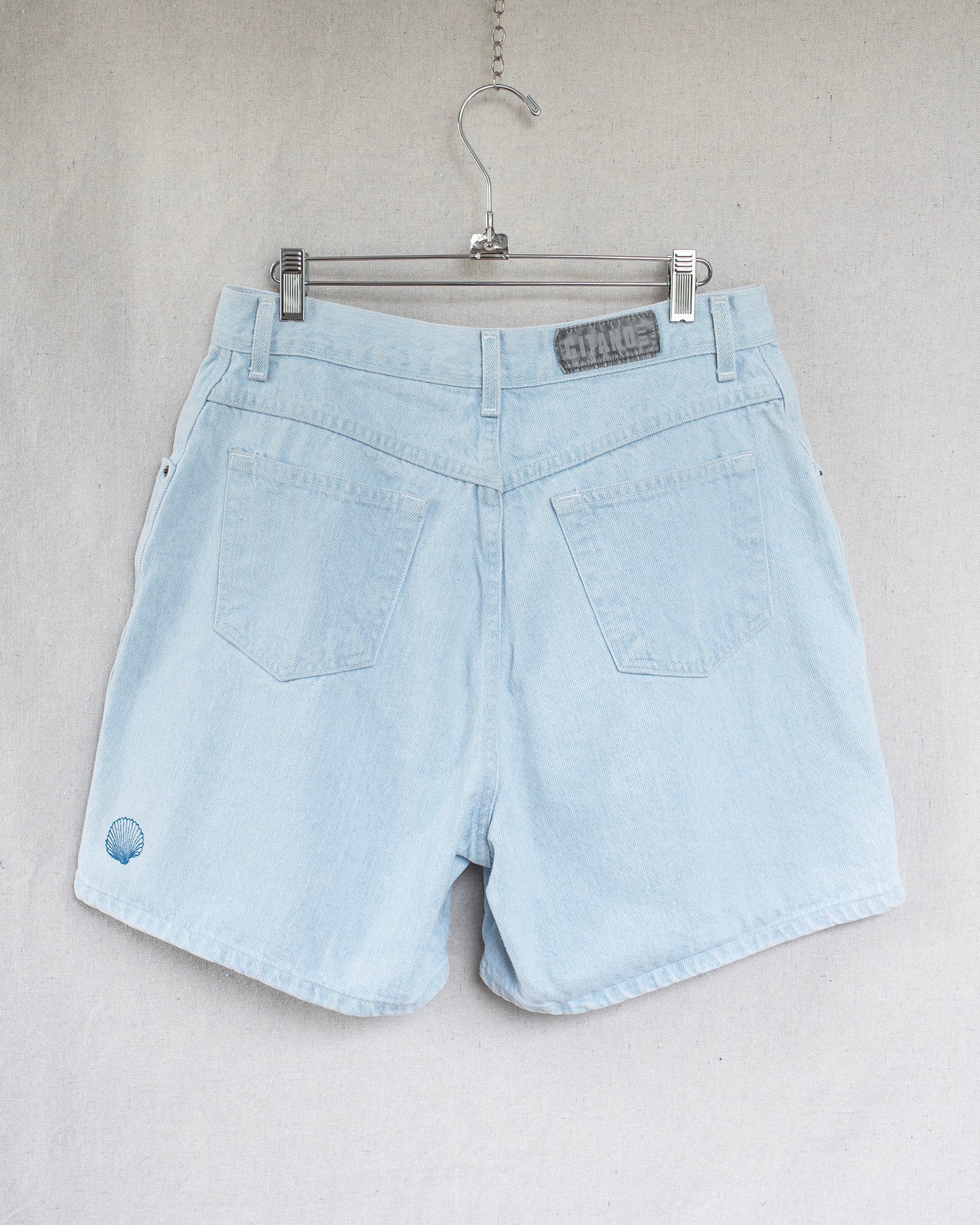 Light blue denim shorts on a hanger against a plain background