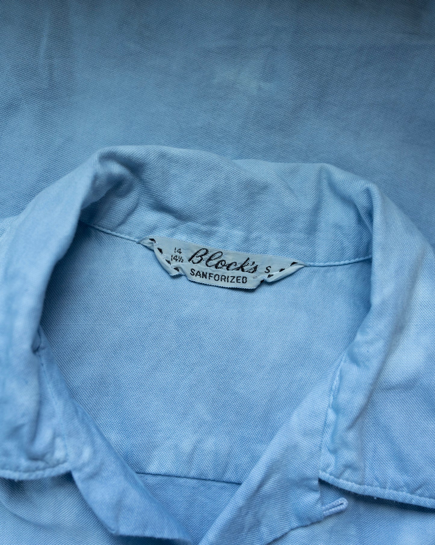 Close-up of a denim shirt with a brand label on a blue background