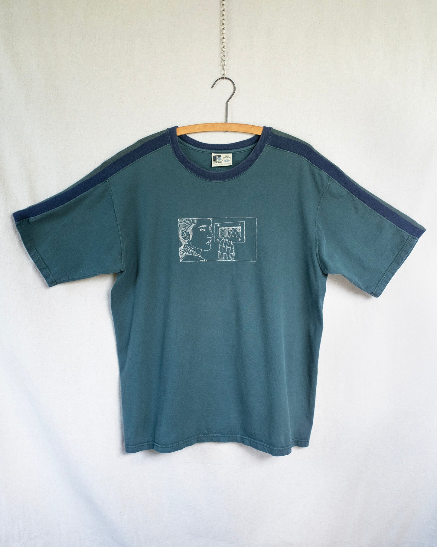 Blue t-shirt with a graphic design on a hanger against a white background