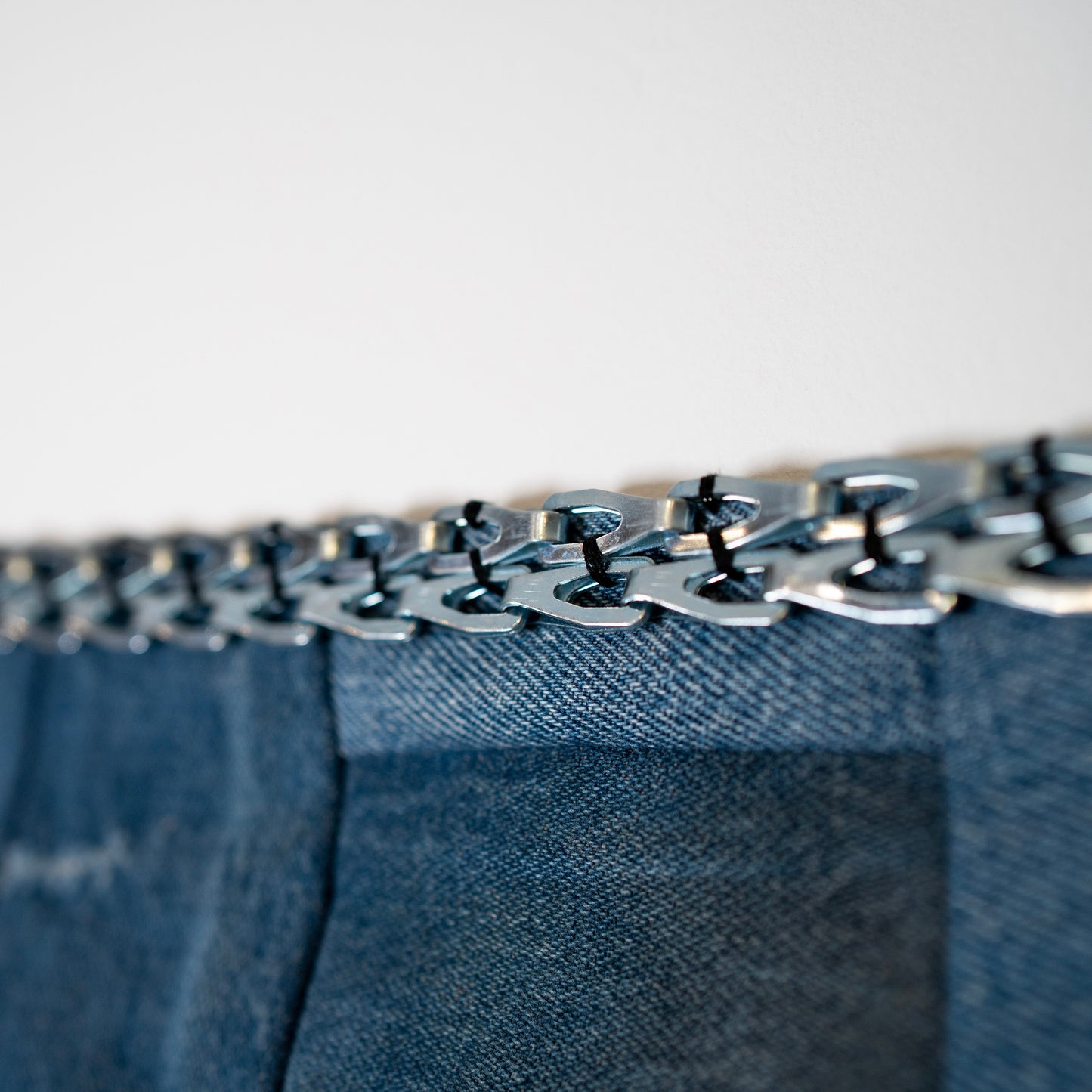 Detail of chain on denim tapestry.