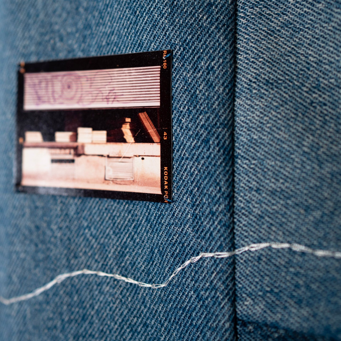 Details of embroidery and photo on denim tapestry.