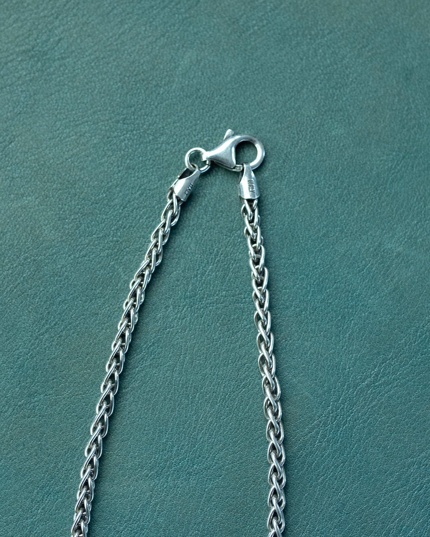 Silver chain necklace with clasp on a teal background