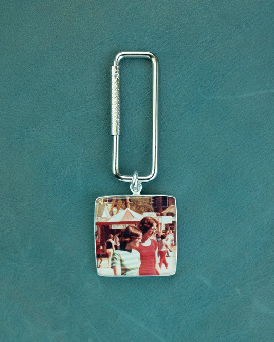 Keychain with a sterling silver photo charm on a teal background