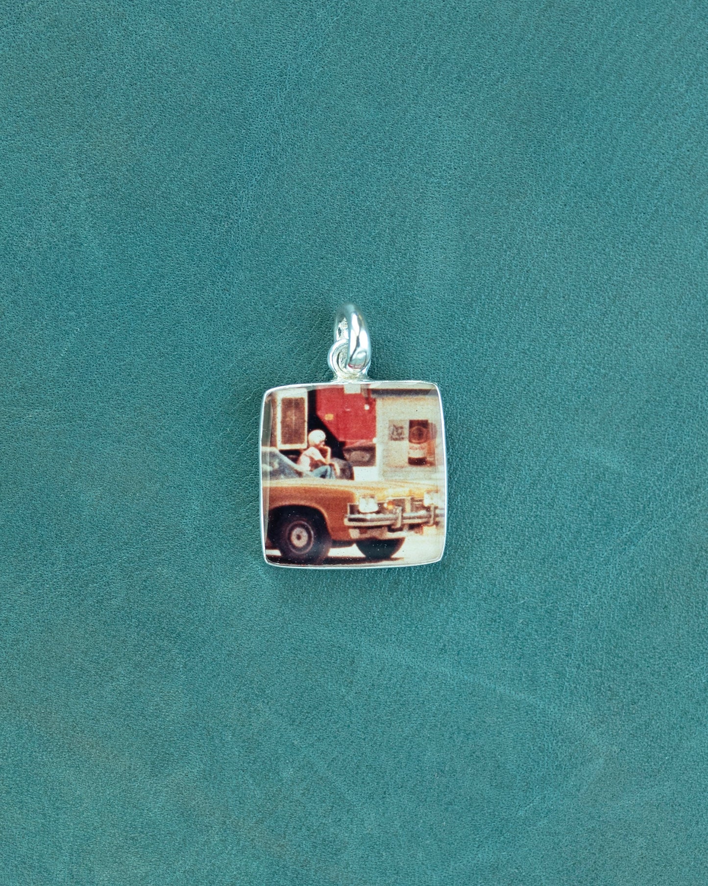 Small square charm with car image.