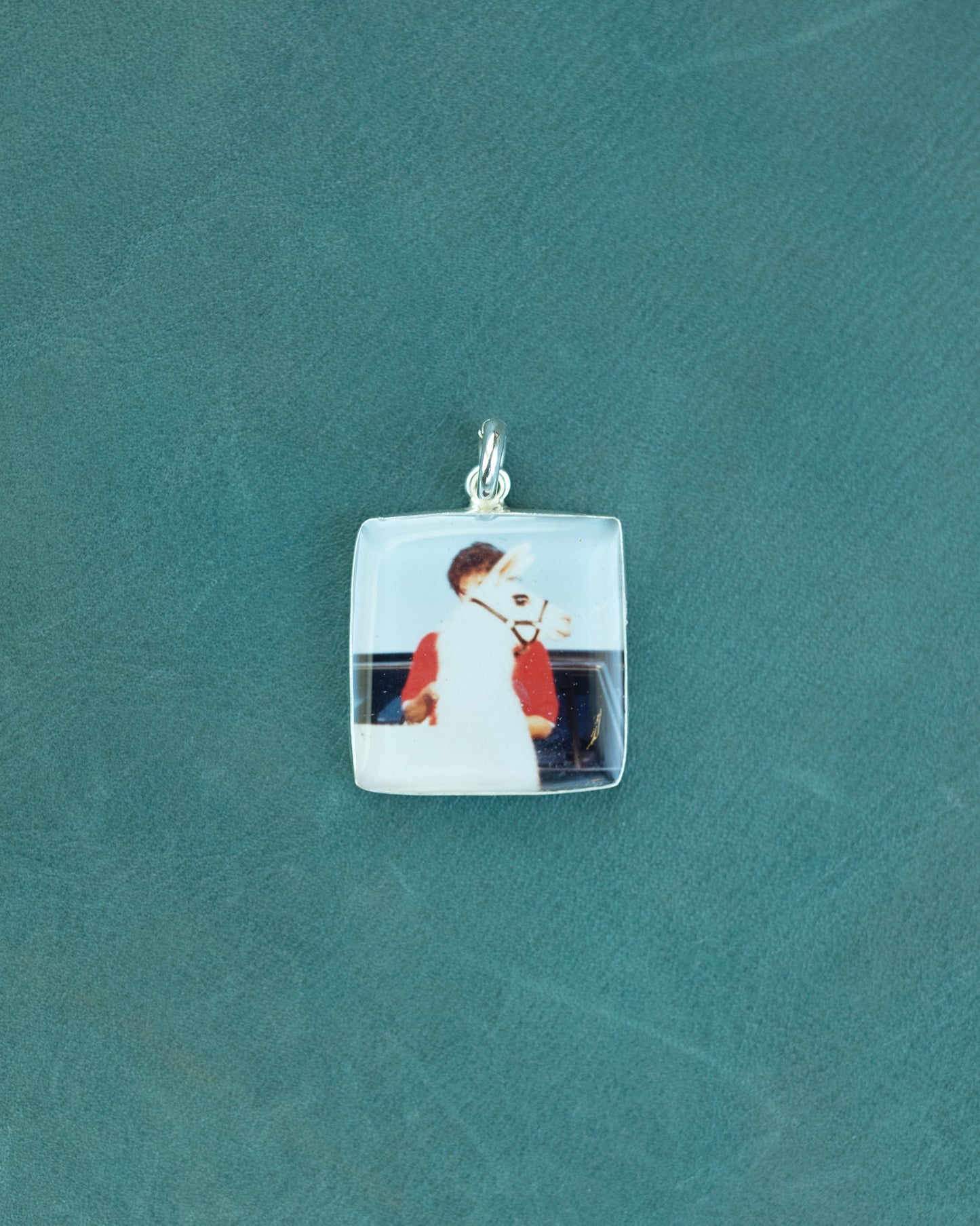 A square charm with a photo of a woman and a llama standing in front of her.