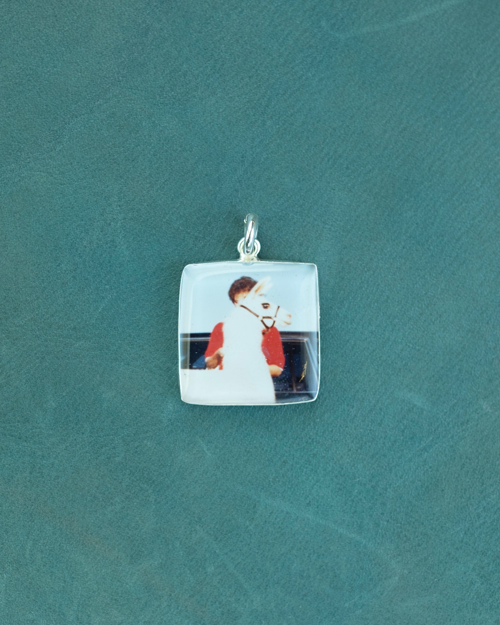 A square charm with a photo of a woman and a llama standing in front of her.