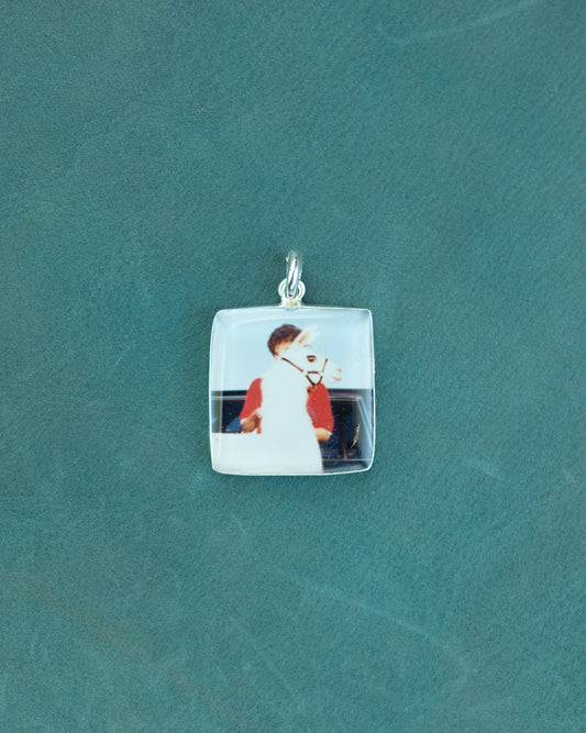 A square charm with a photo of a woman and a llama standing in front of her.