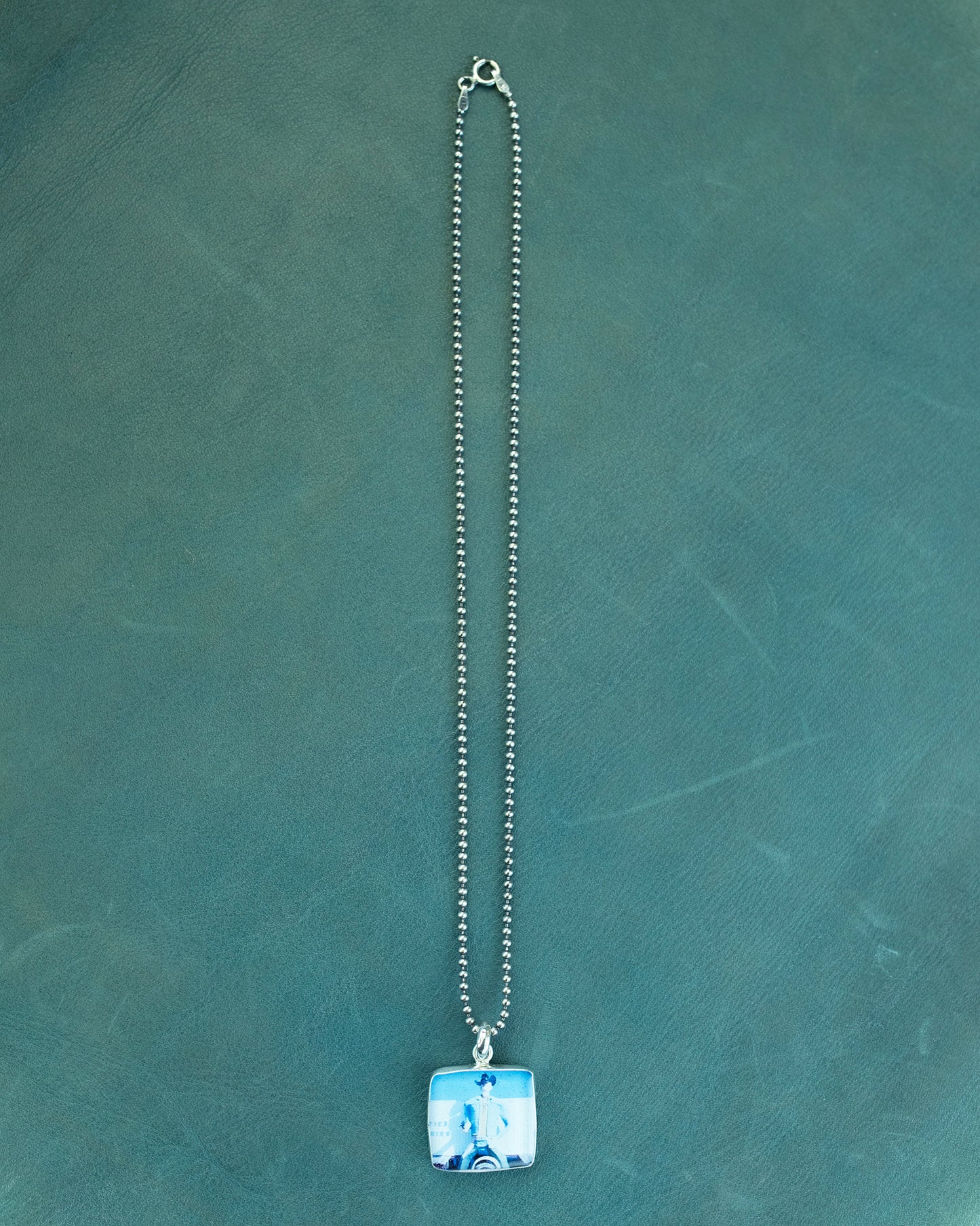 Necklace with a square pendant on a green textured background