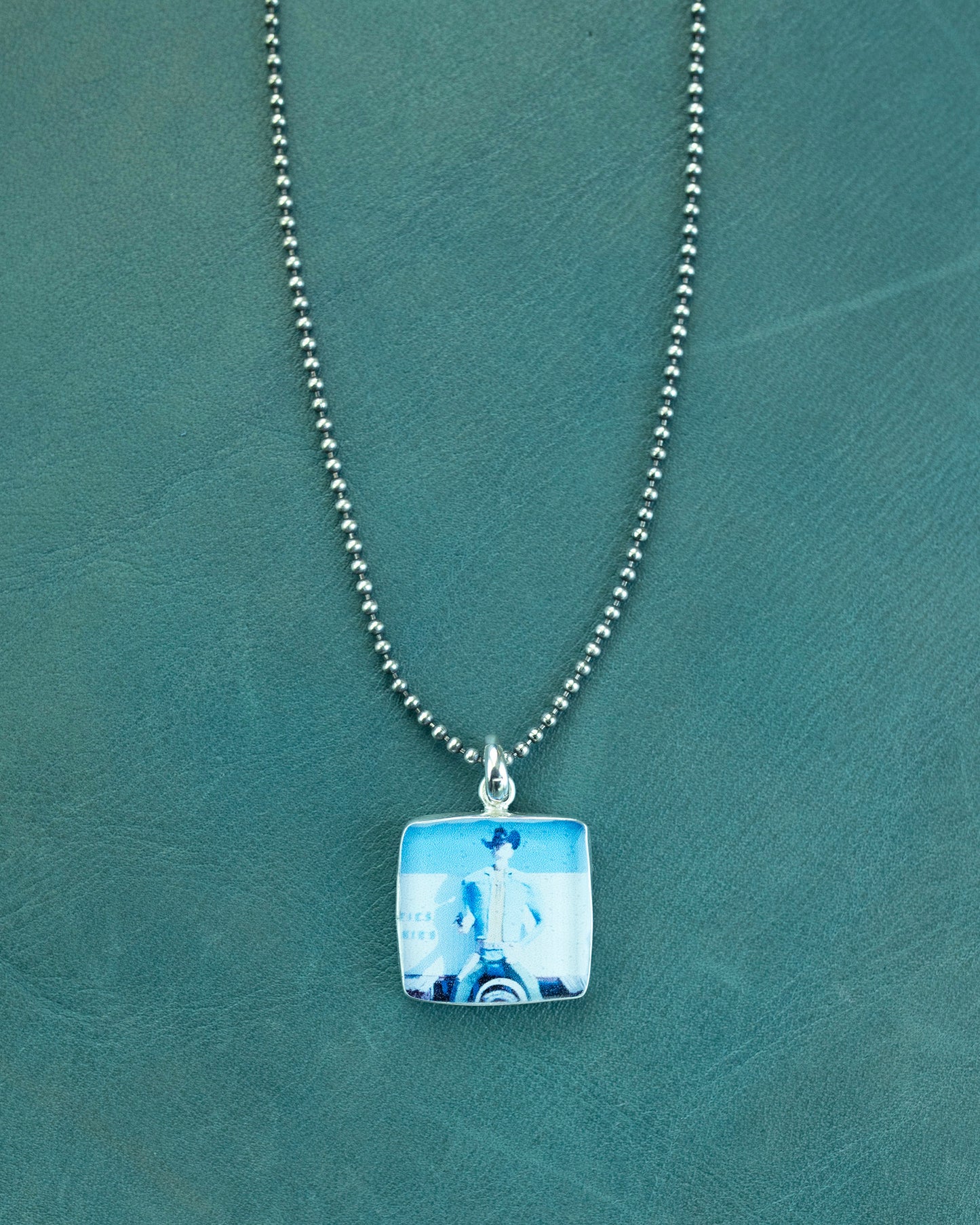 Necklace with a square pendant on a green textured background