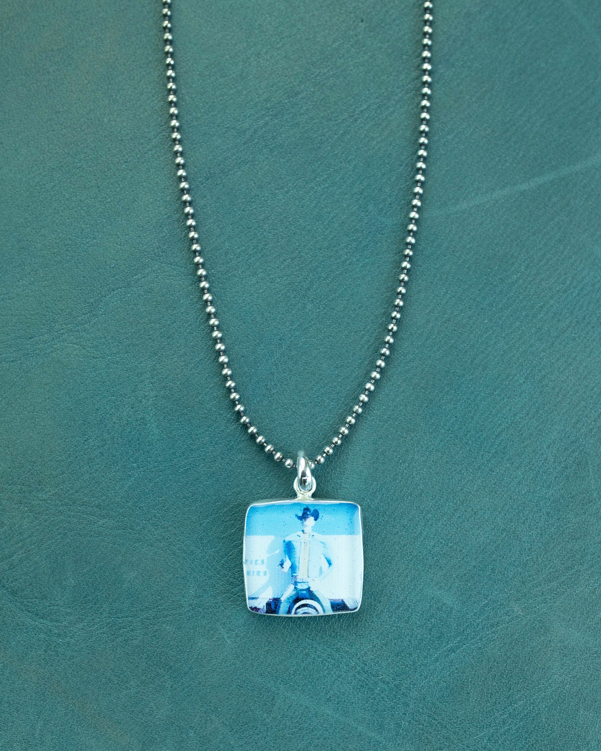 Necklace with a square pendant on a green textured background