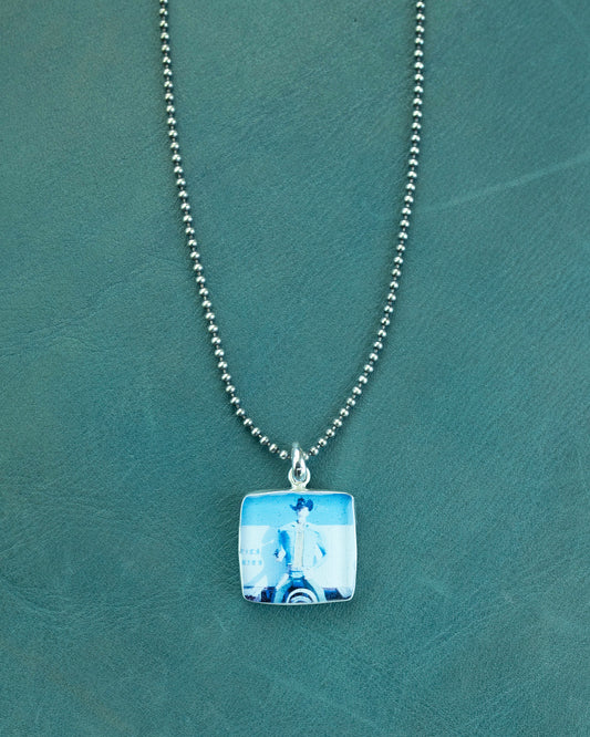Necklace with a square pendant on a green textured background