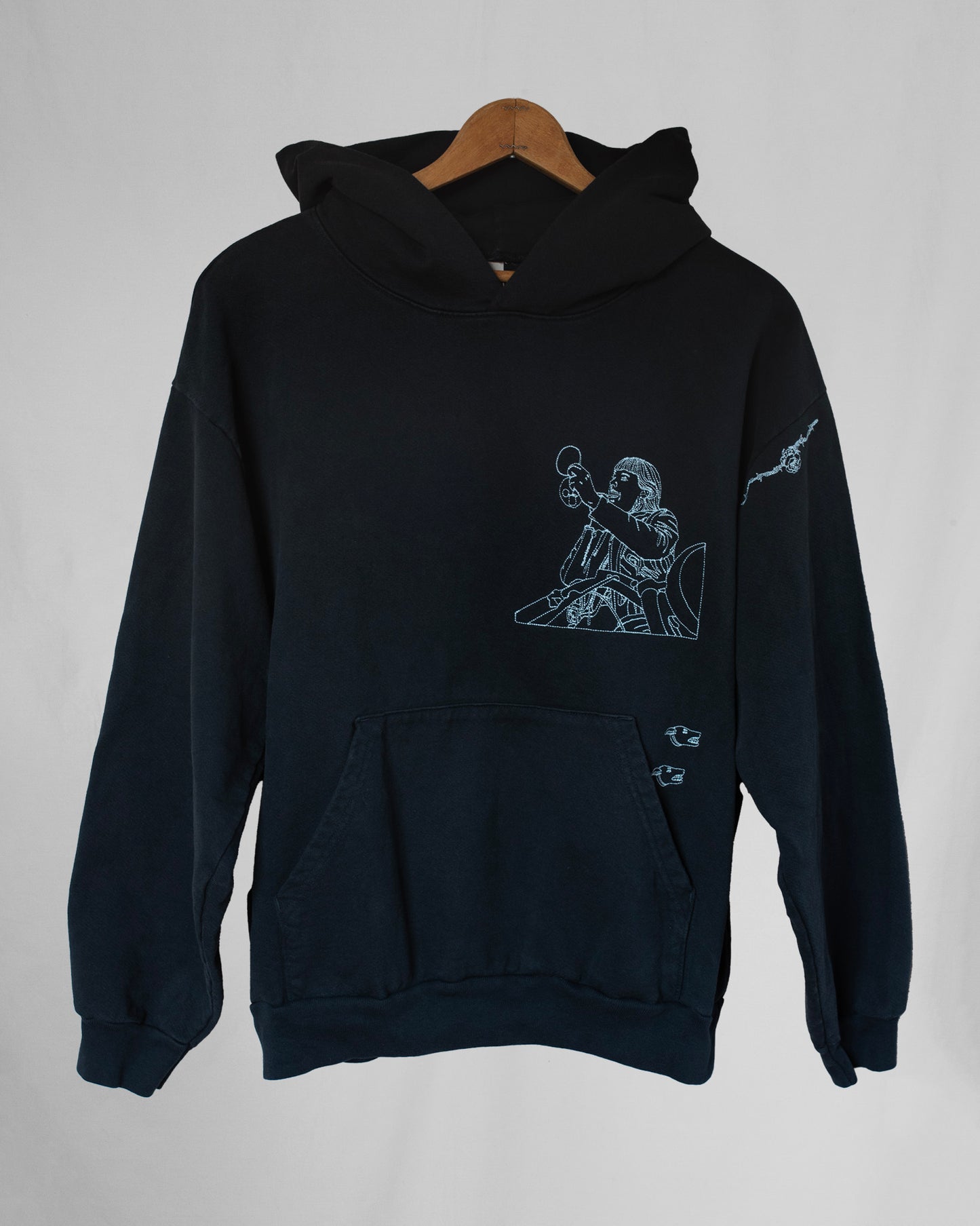 Black hoodie with embroidery designs on a gray background