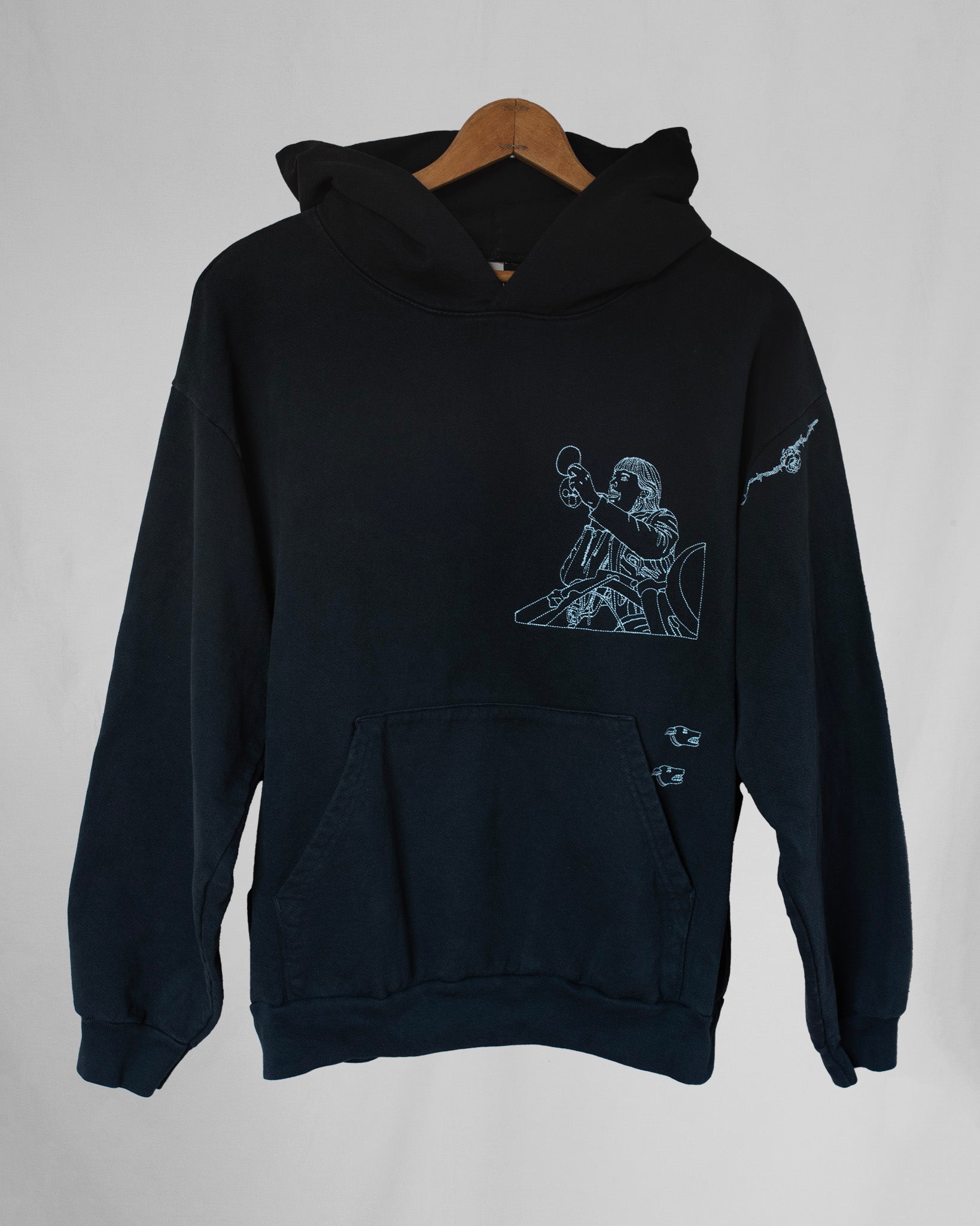 Black hoodie with embroidery designs on a gray background