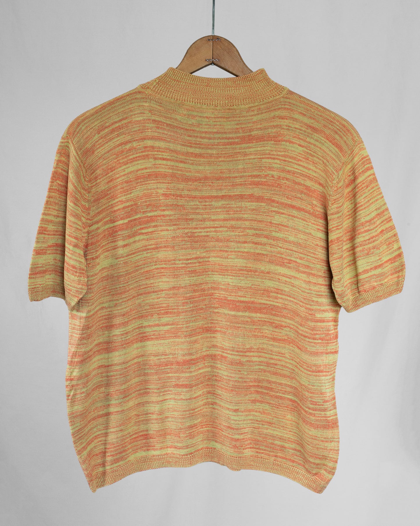 Knitted sweater on a hanger against a plain background