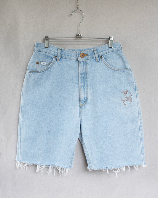 Light blue denim shorts with an armadillo embroidery on a gray background