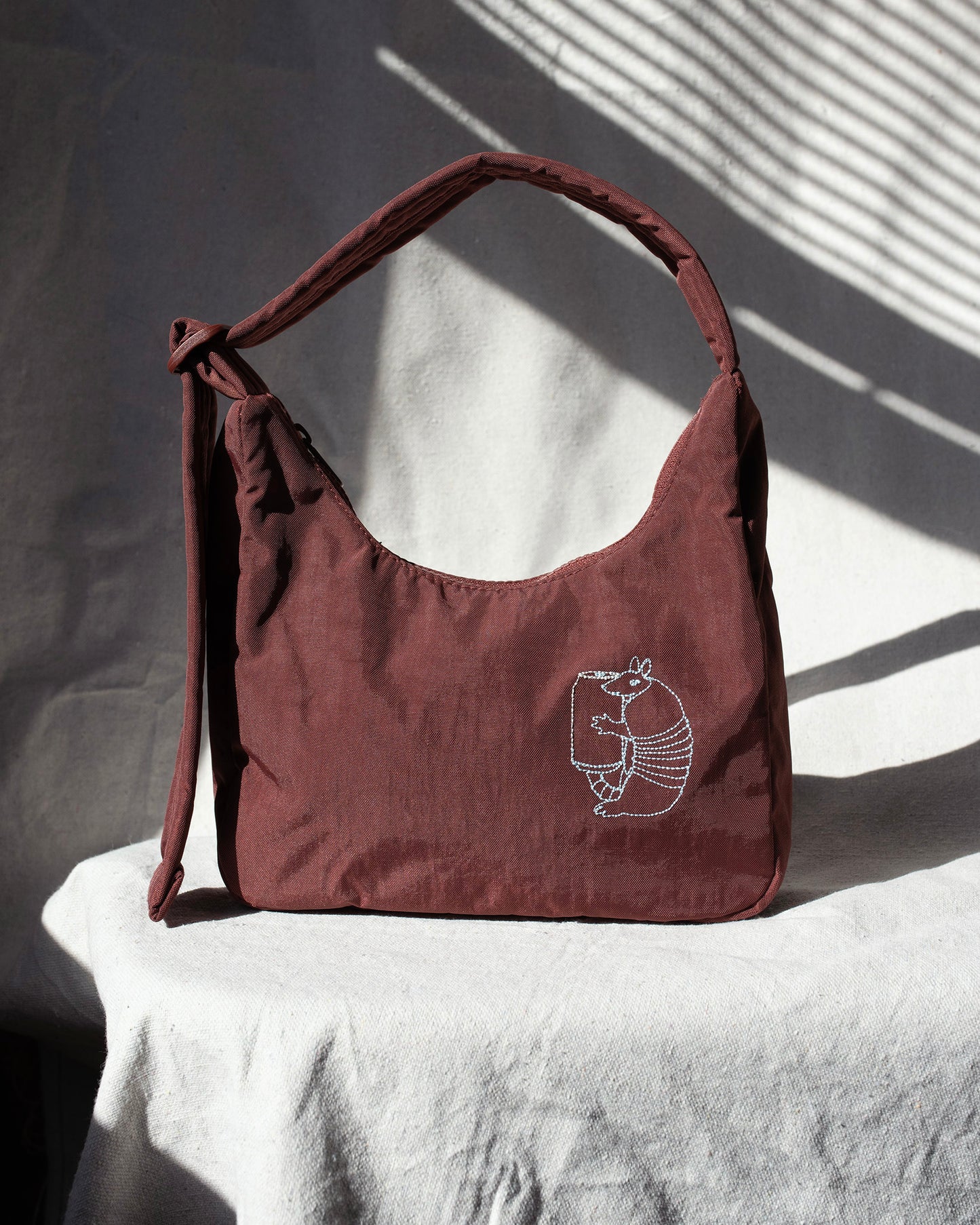 Mahogany handbag with a embroidery on a white surface with shadows