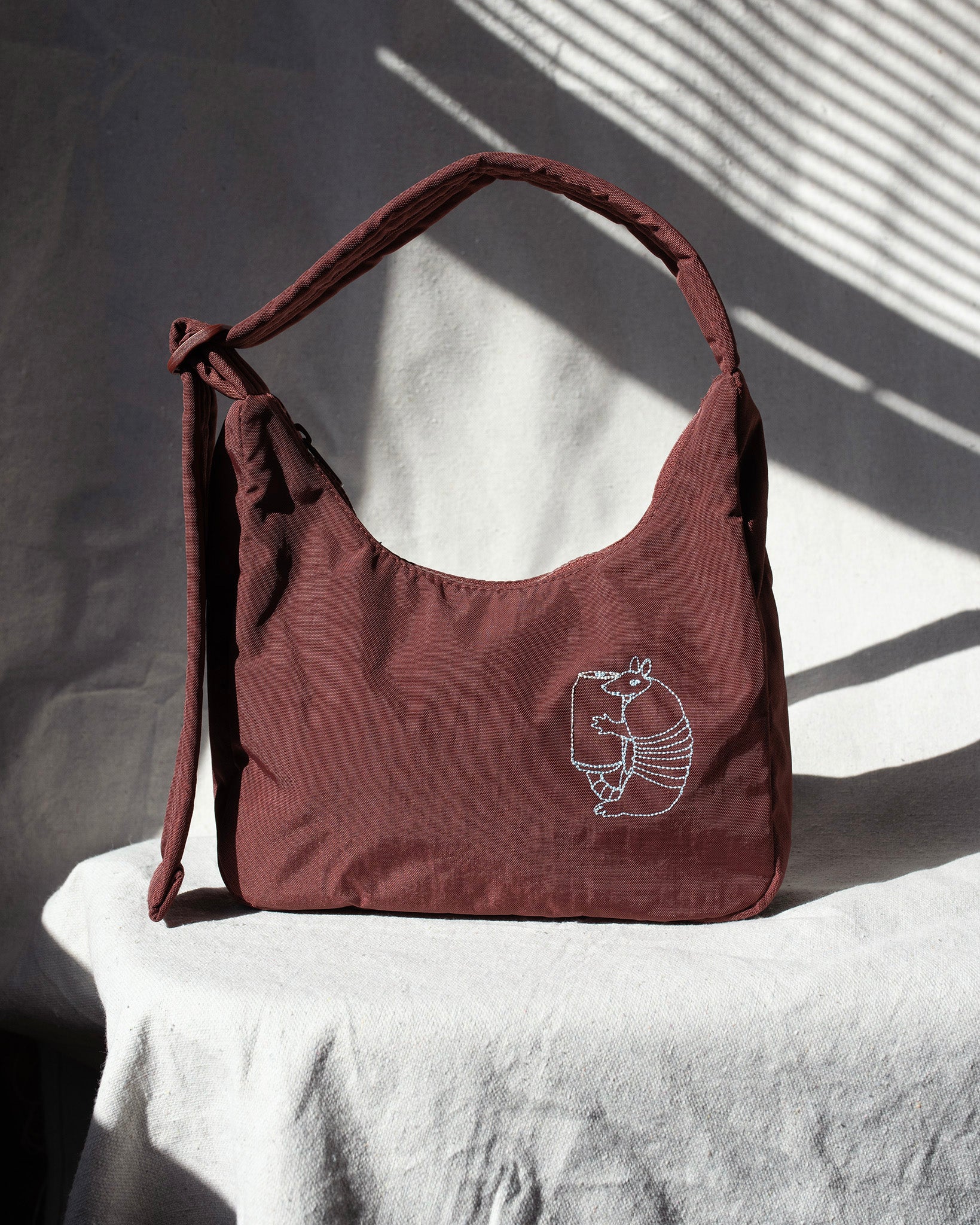 Mahogany handbag with a embroidery on a white surface with shadows
