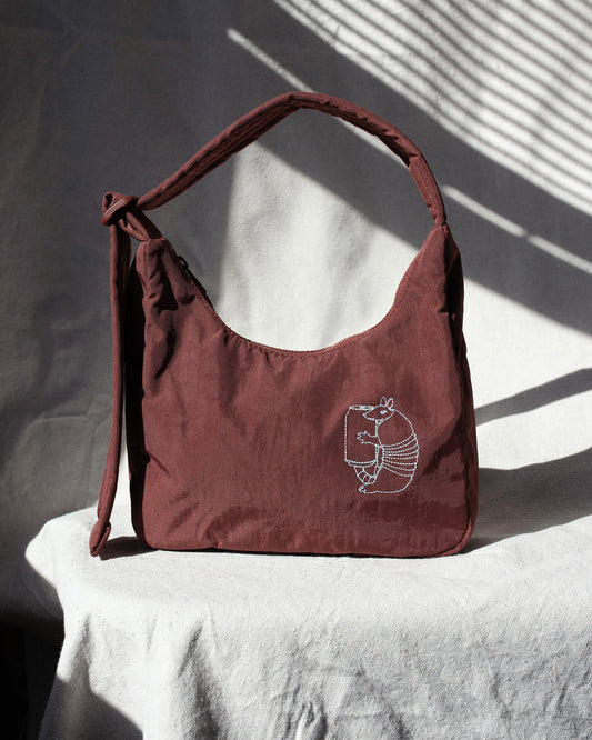 Mahogany handbag with a embroidery on a white surface with shadows