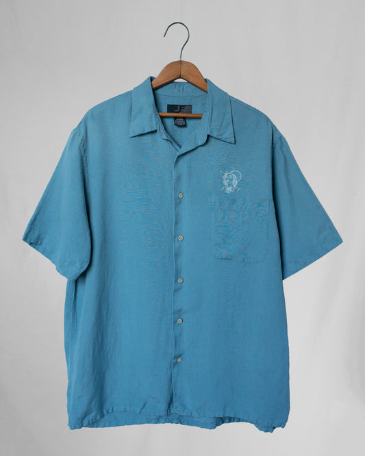 Blue short-sleeve shirt with a cowgirl embroidery on a hanger against a gray background