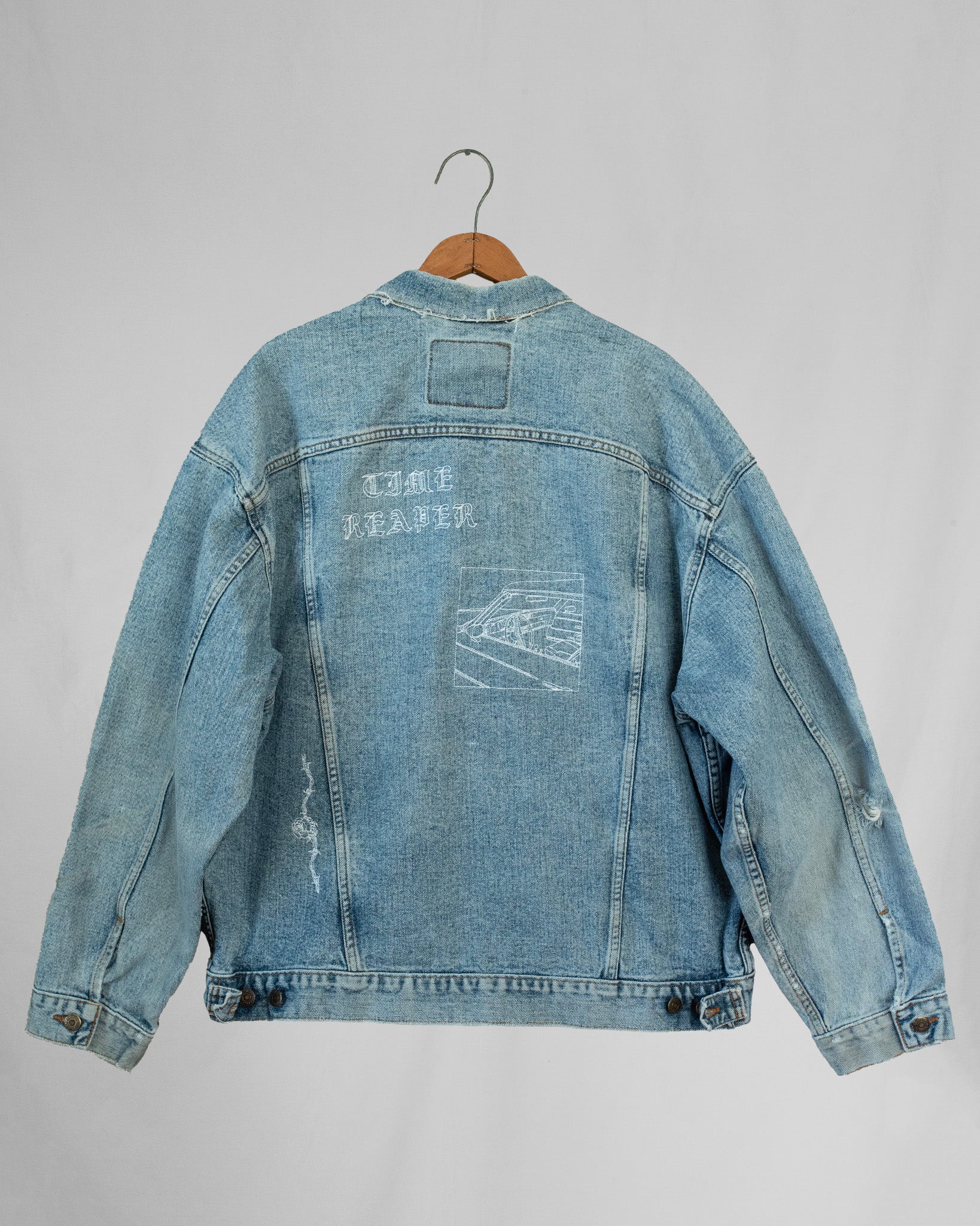 1990s Levis denim jacket with embroidery and a boxy fit, displayed on a hanger against a white background.