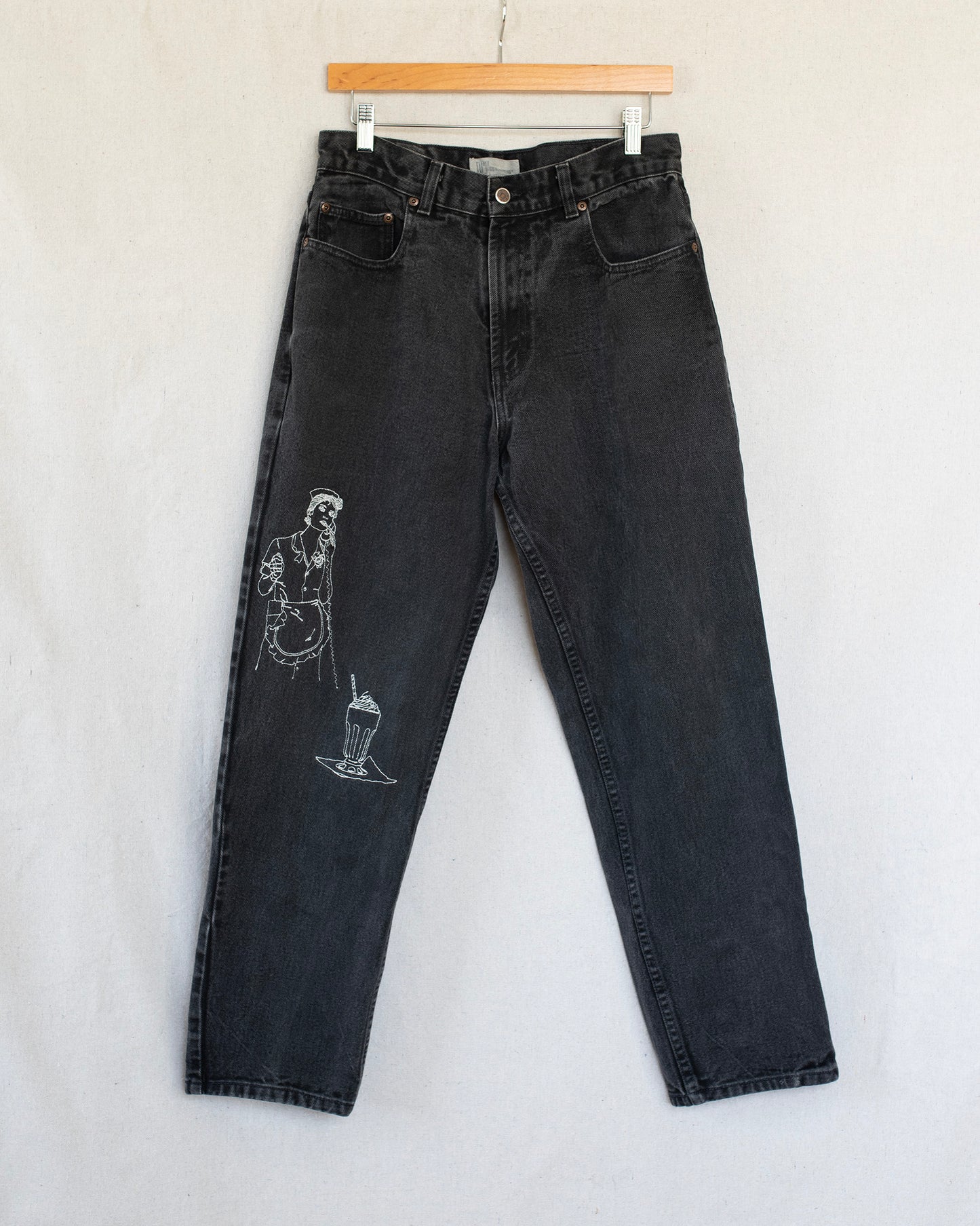 Black jeans with embroideries on a light gray background