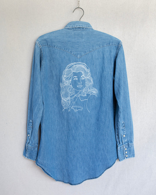 Blue denim shirt with a white embroidered design on a gray background