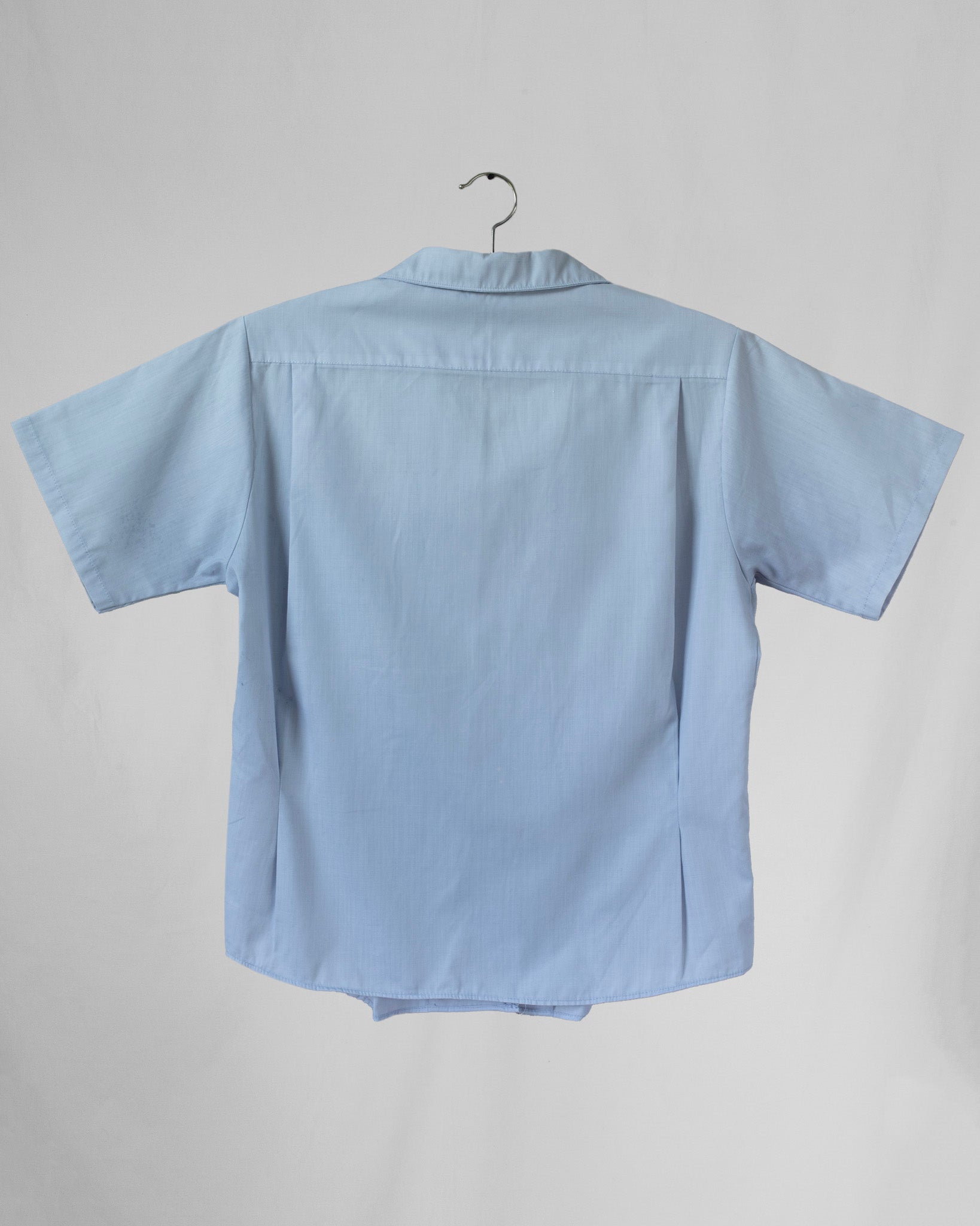 Light blue shirt on a hanger against a gray background