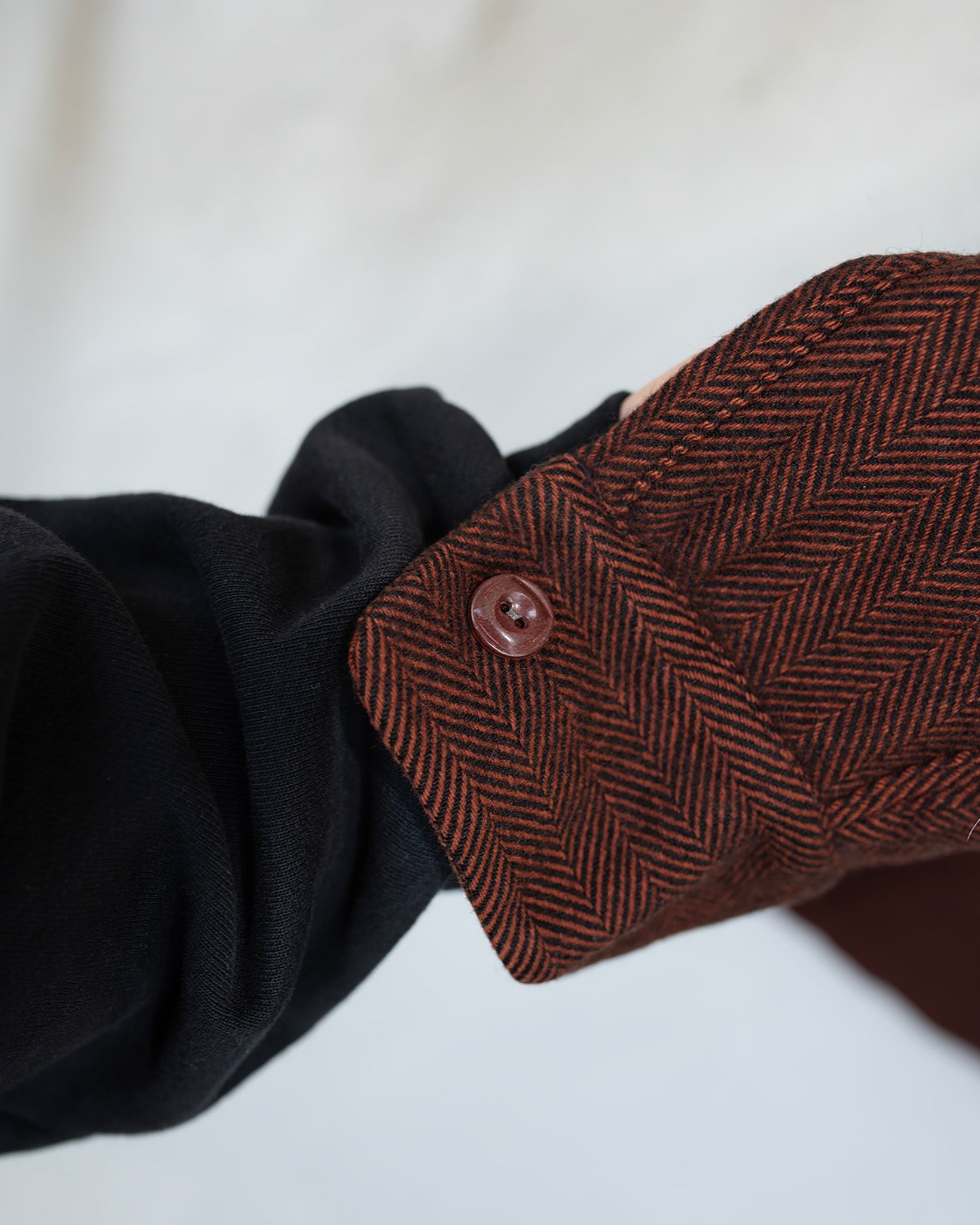 Close-up of a brown herringbone fabric with button.