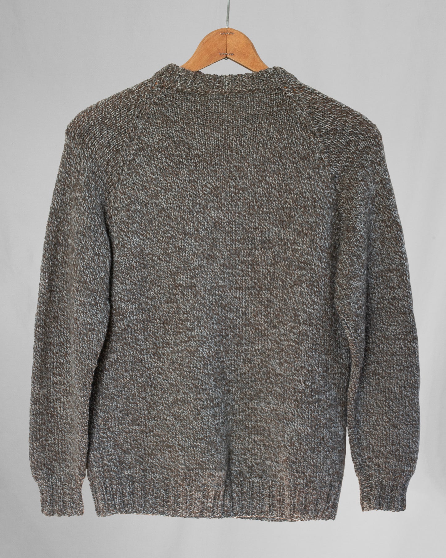 Brown knitted sweater on a wooden hanger against a light gray background