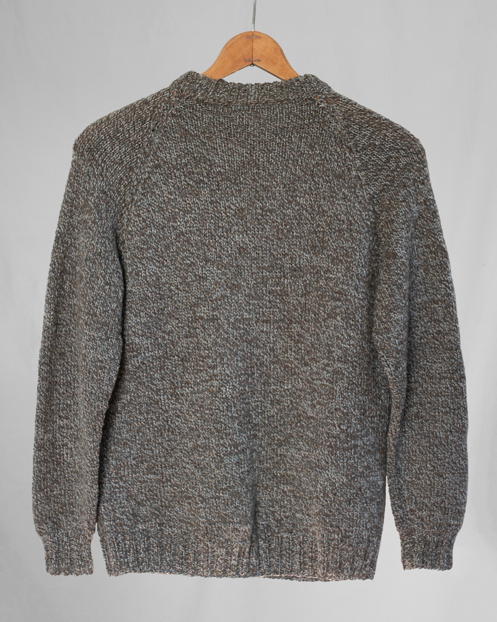 Brown knitted sweater on a wooden hanger against a light gray background