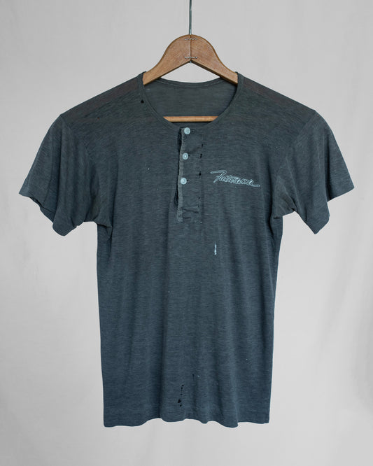 Gray shirt with embroidery on a hanger against a plain background