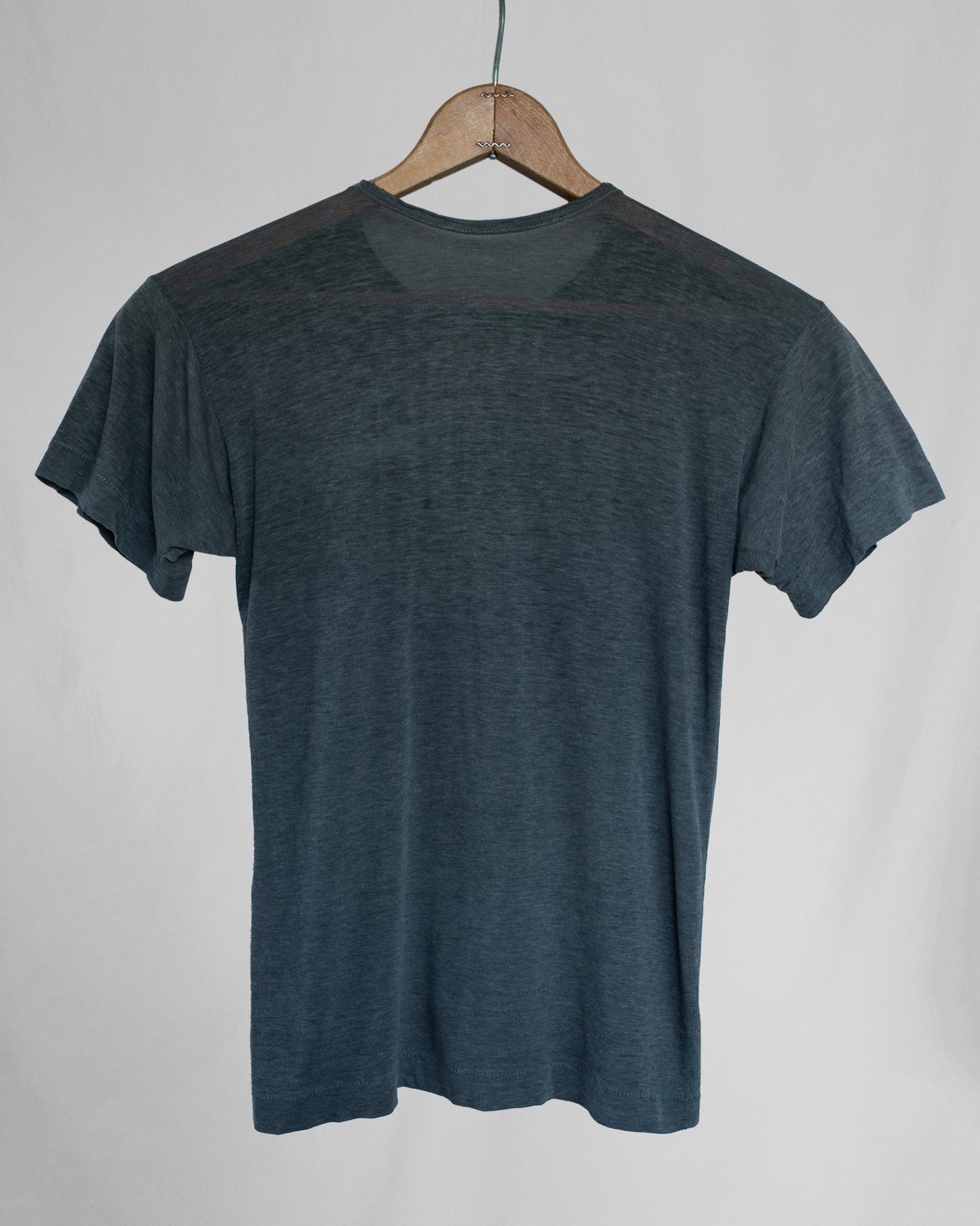Gray t-shirt on a wooden hanger against a plain background