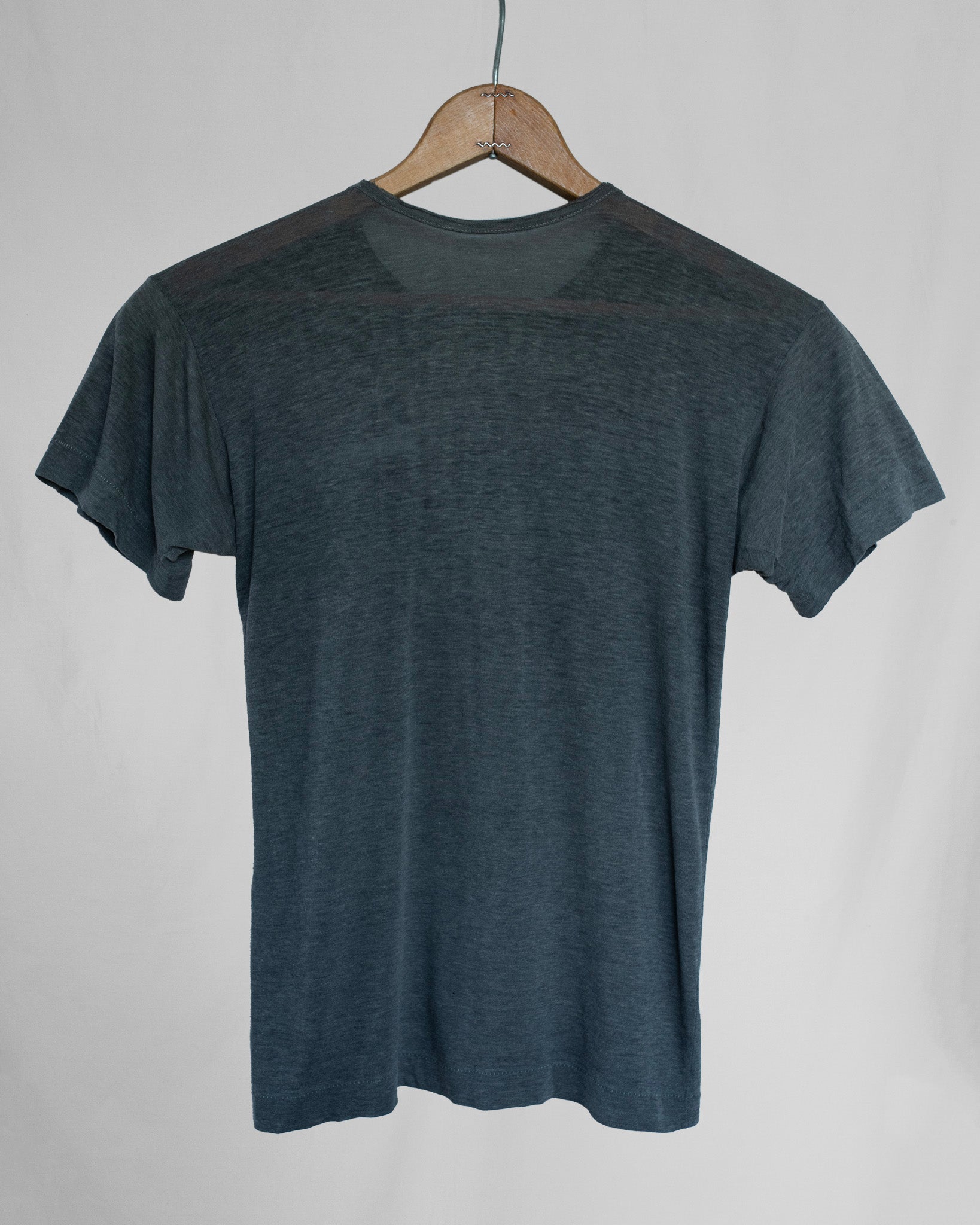 Gray t-shirt on a wooden hanger against a plain background